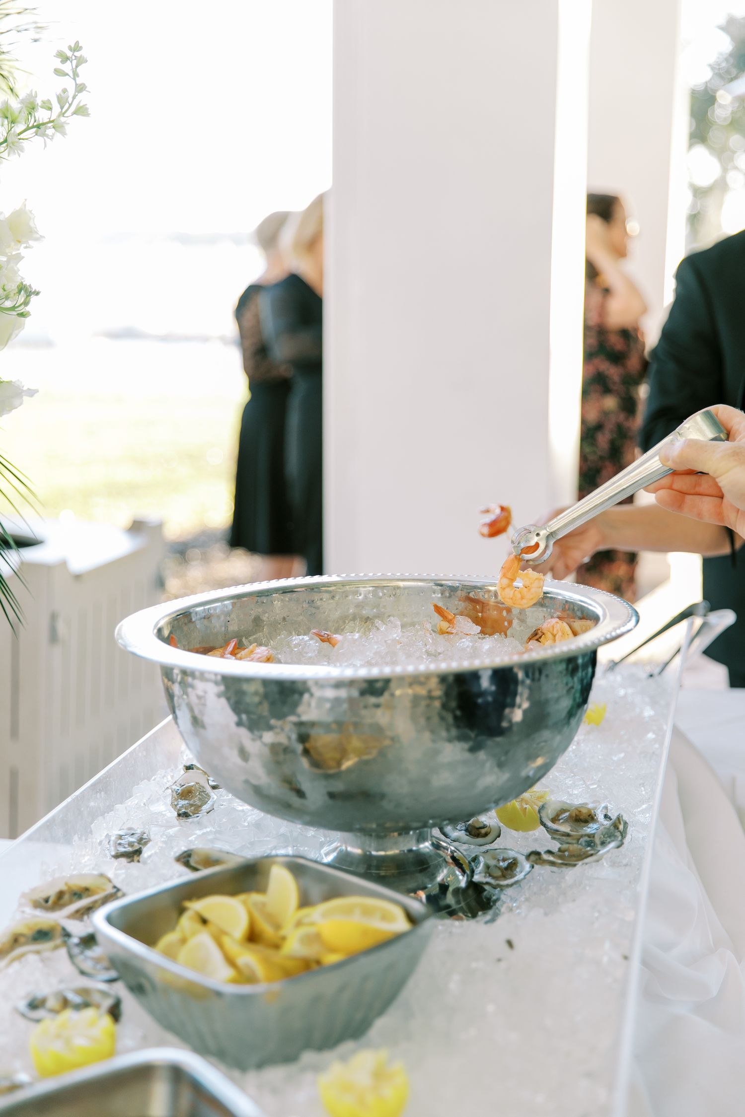 A buffet serving station with a silver chafing dish and lemon wedges at an elegant event.