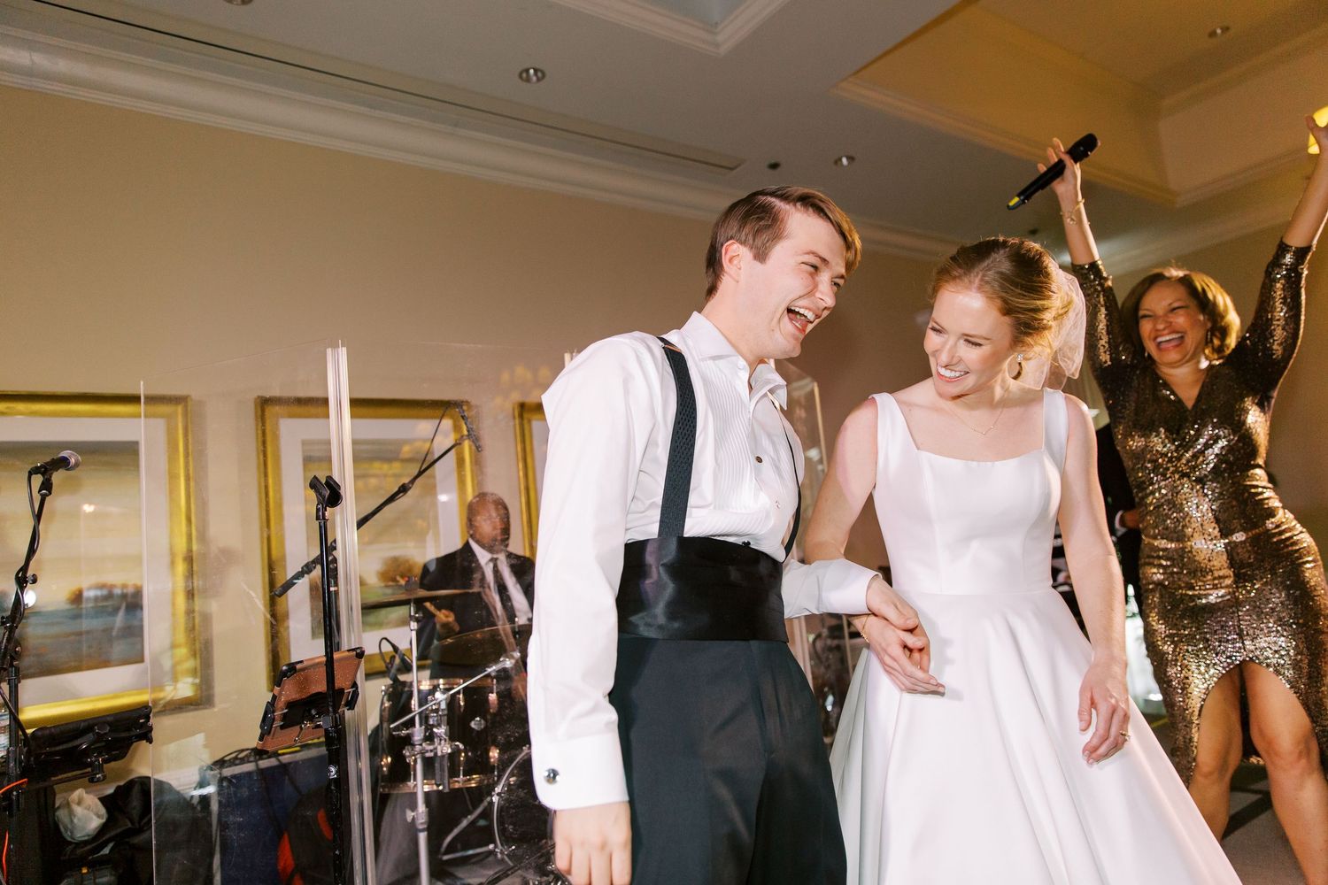 Couple dancing together at their wedding reception with band performing in background.