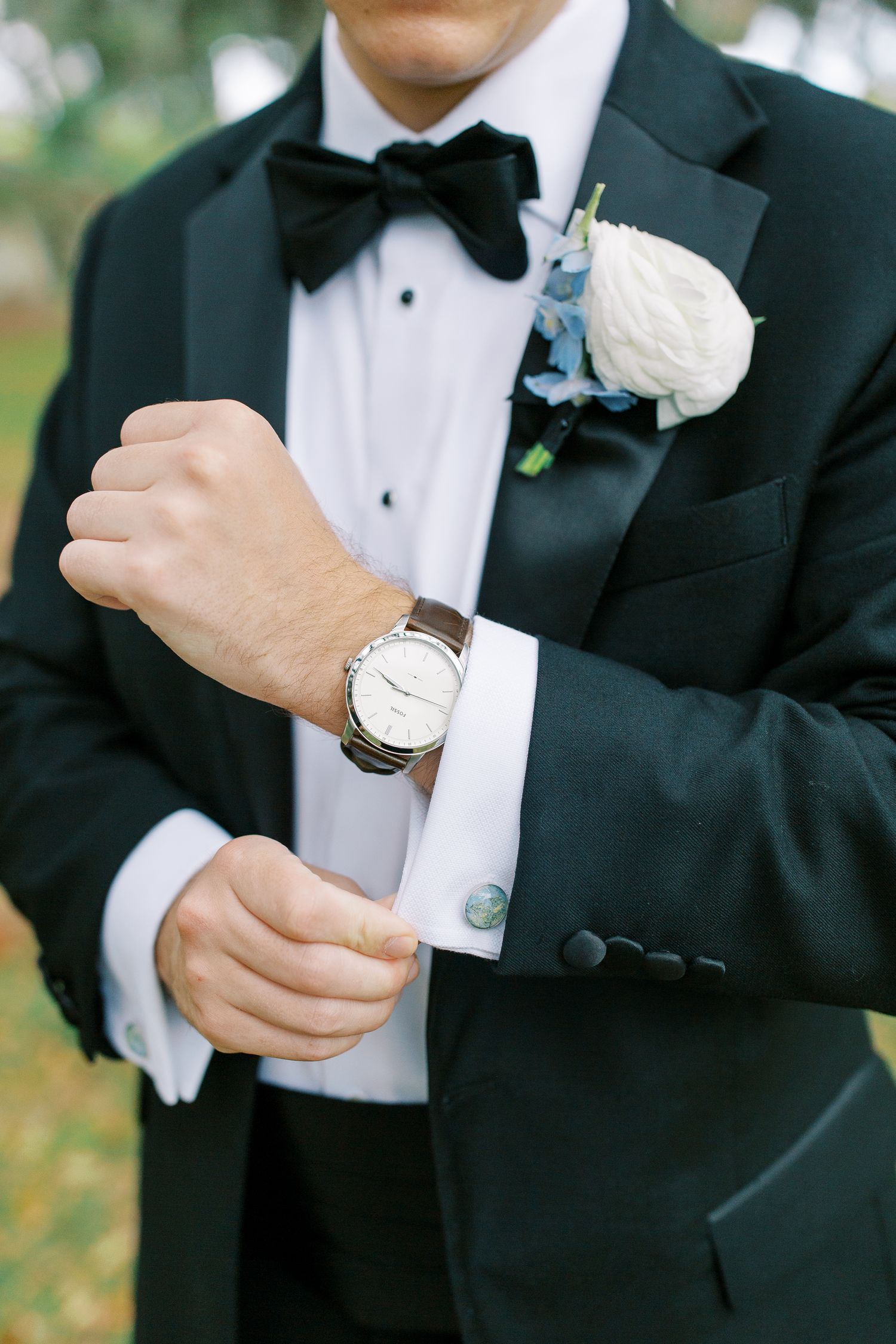 Detail shot of groom's formal attire with watch and blue boutonniere.