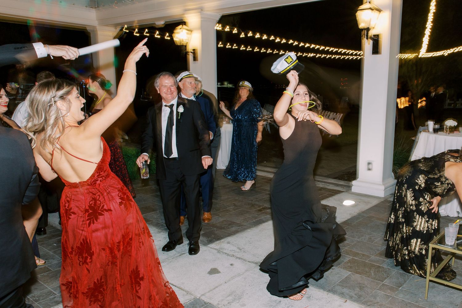 Wedding guests enjoying themselves dancing on an outdoor patio with string lights overhead.