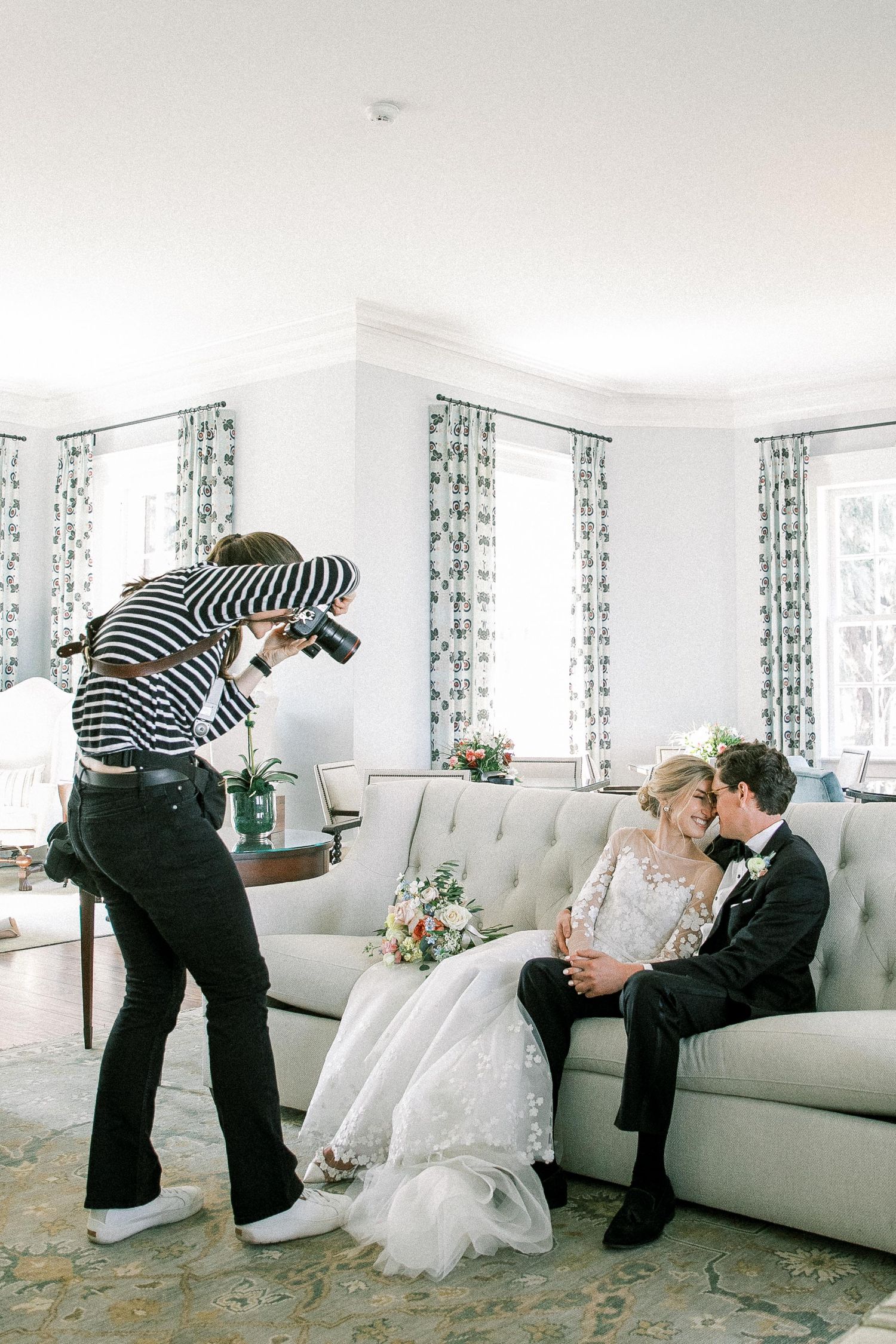 Photographer taking photos of a bride and groom sitting on a couch at The Ford Field in Richmond Hill, GA.