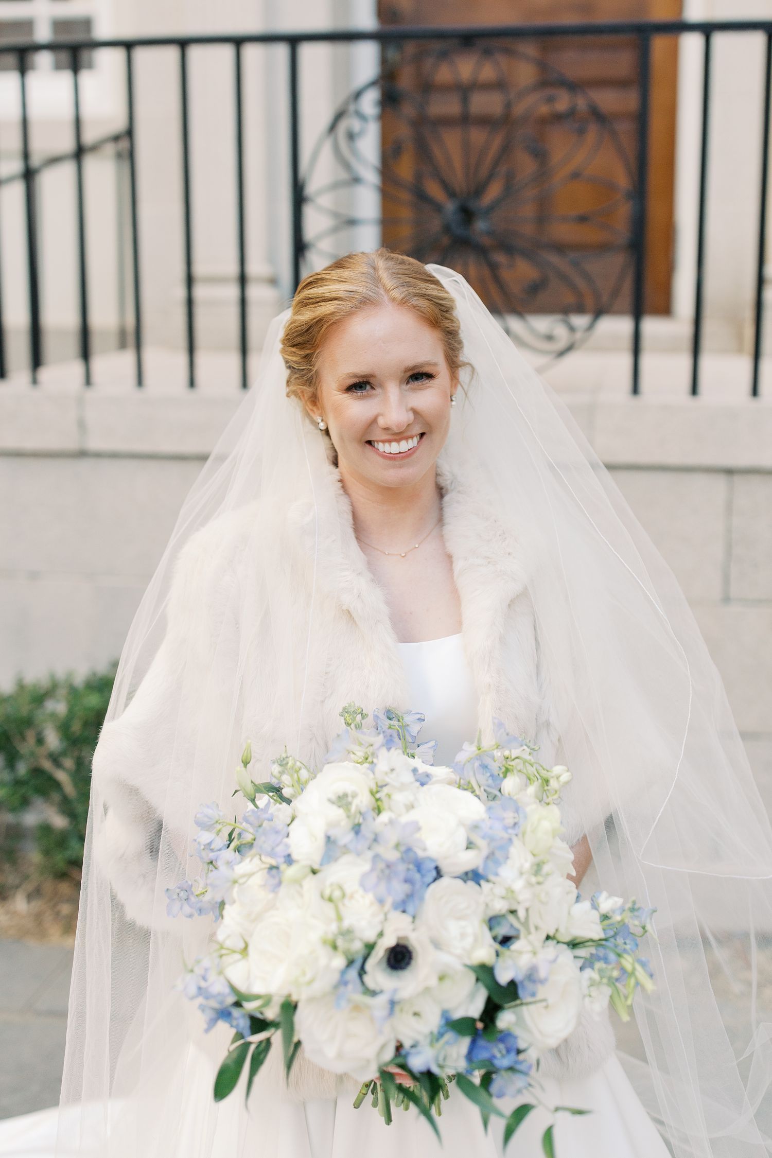 Bridal portrait with blue and white bouquet featuring anemones and roses.