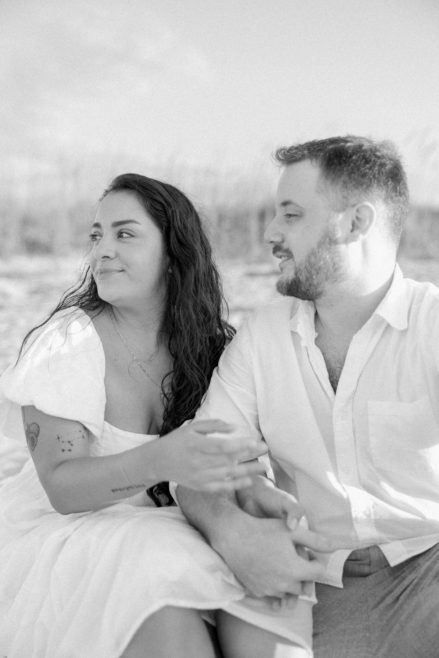 Black and white portrait of a romantic couple sharing intimate moments on the beach.