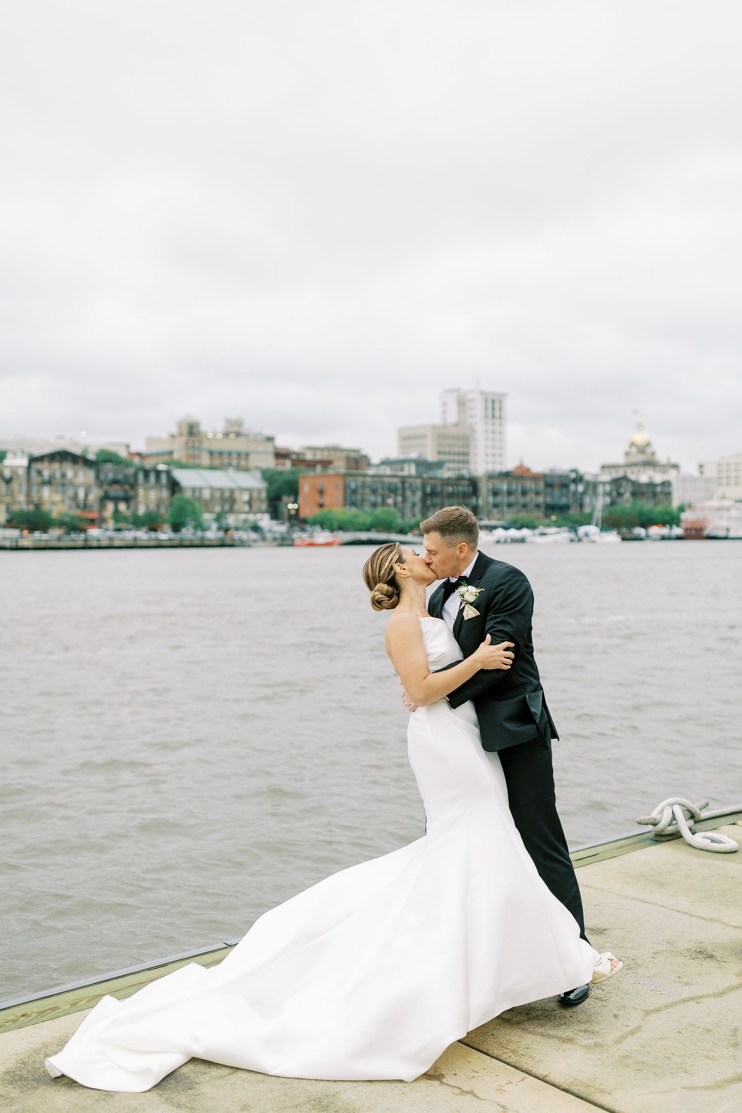 Waterfront wedding portrait with cityscape backdrop and flowing white dress at The Westin Savannah.