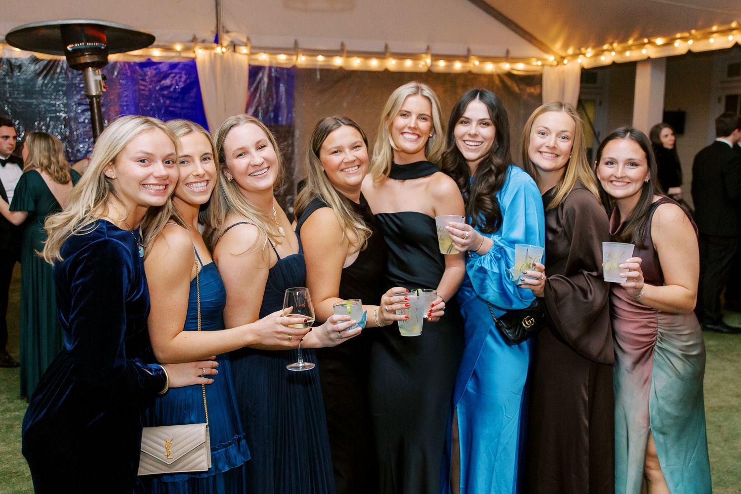 Wedding guests in blue and black attire mingle during evening reception celebration.