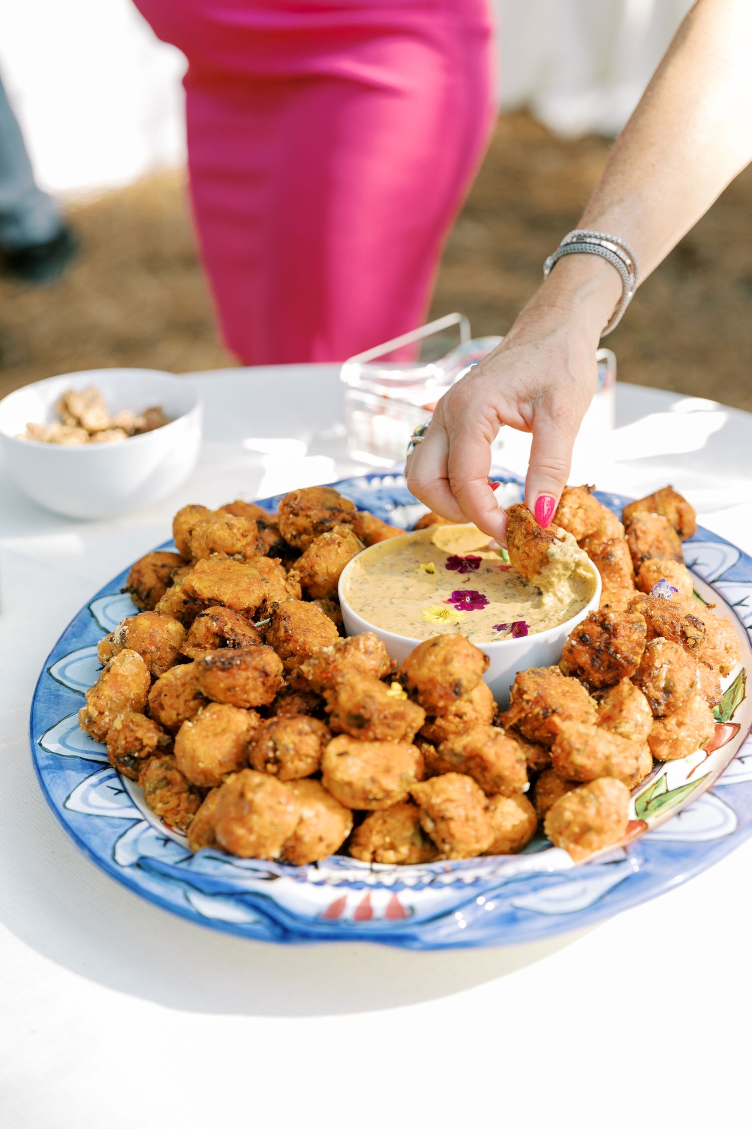 A platter of golden fried appetizers with dipping sauce being served at an event.