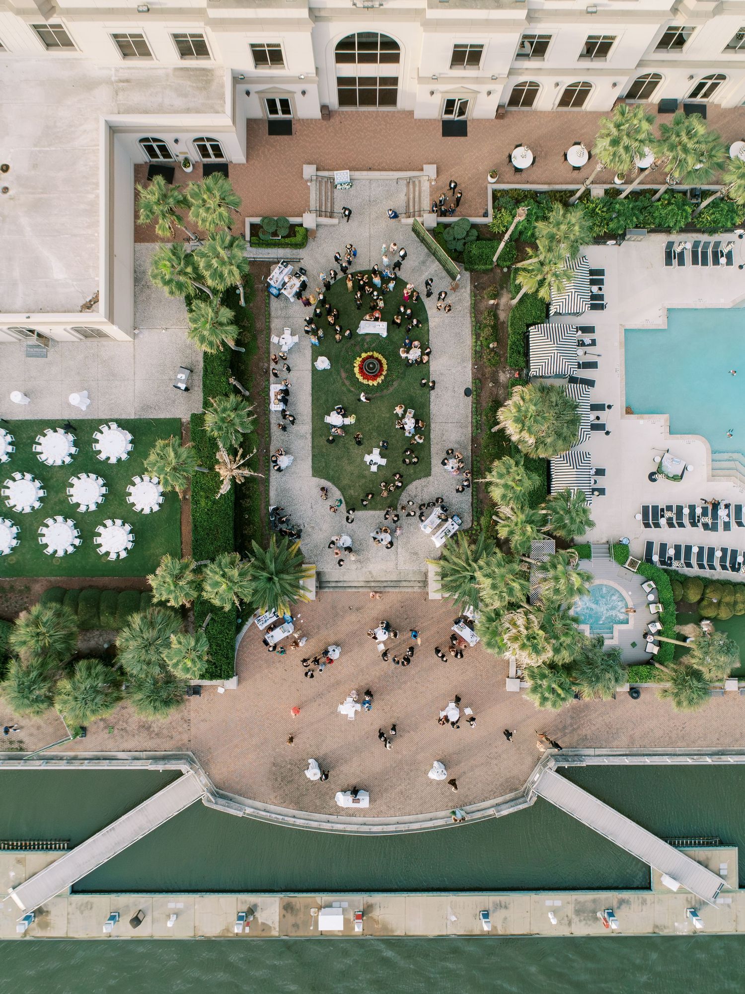 Aerial view of a luxury hotel pool deck with lounge chairs, umbrellas, and landscaping arranged in a geometric pattern.