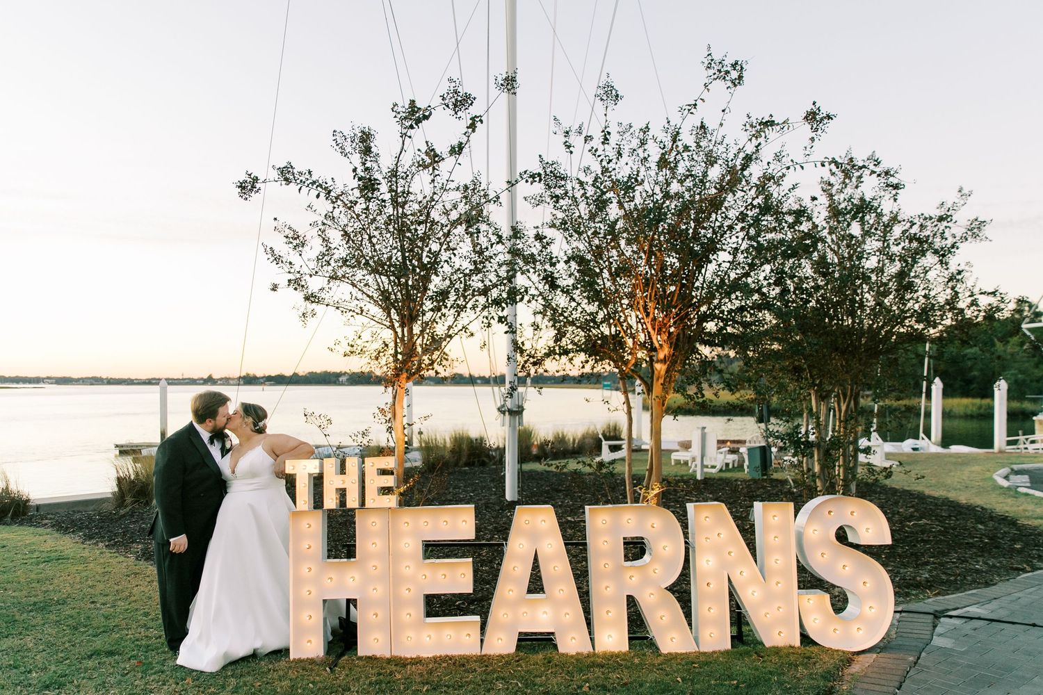 Sunset wedding photo with large illuminated 'THE FEARNS' letters on display.