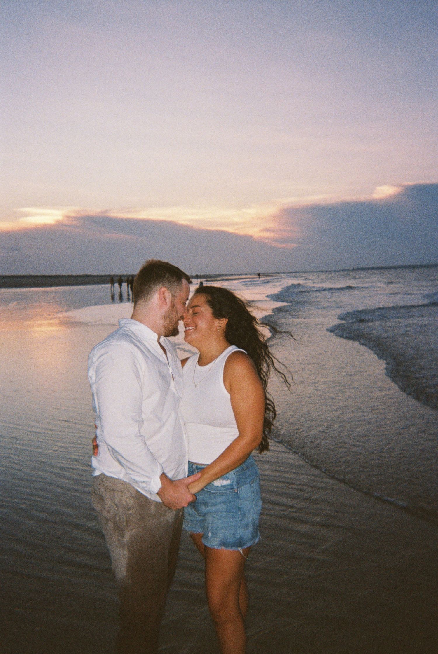 A romantic sunset beach photoshoot with waves and coastal scenery in the background.