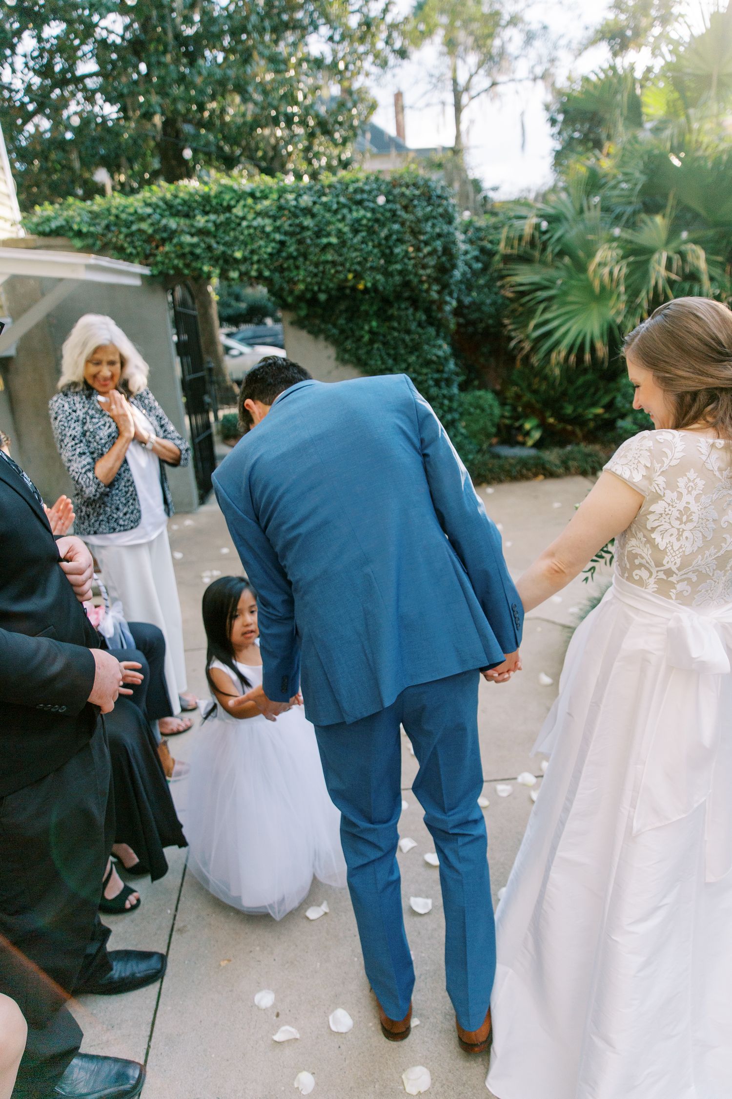 Wedding party members gather on stone steps outside during an outdoor celebration.