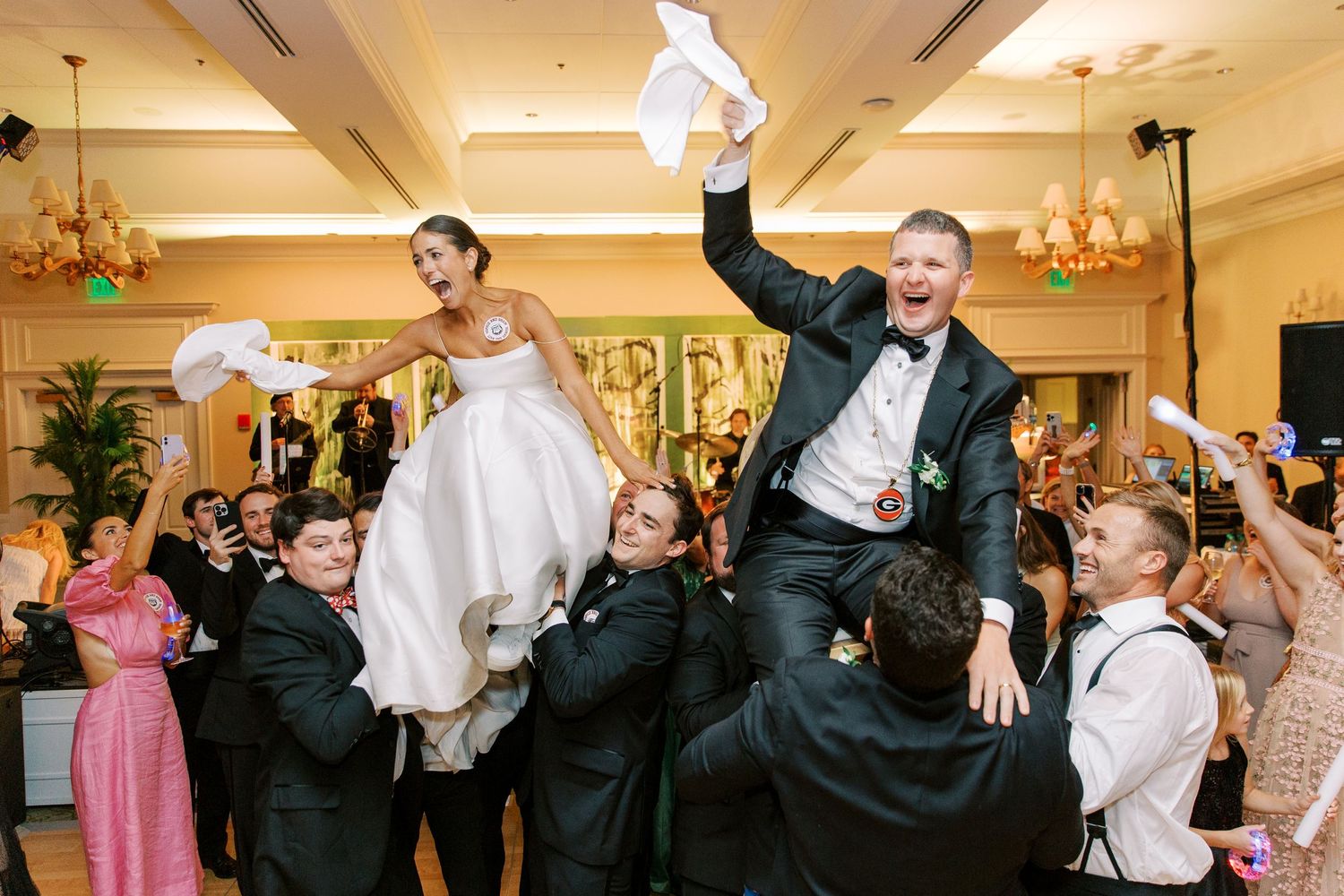 Wedding party lifts newlyweds in celebration during a joyous reception dance.