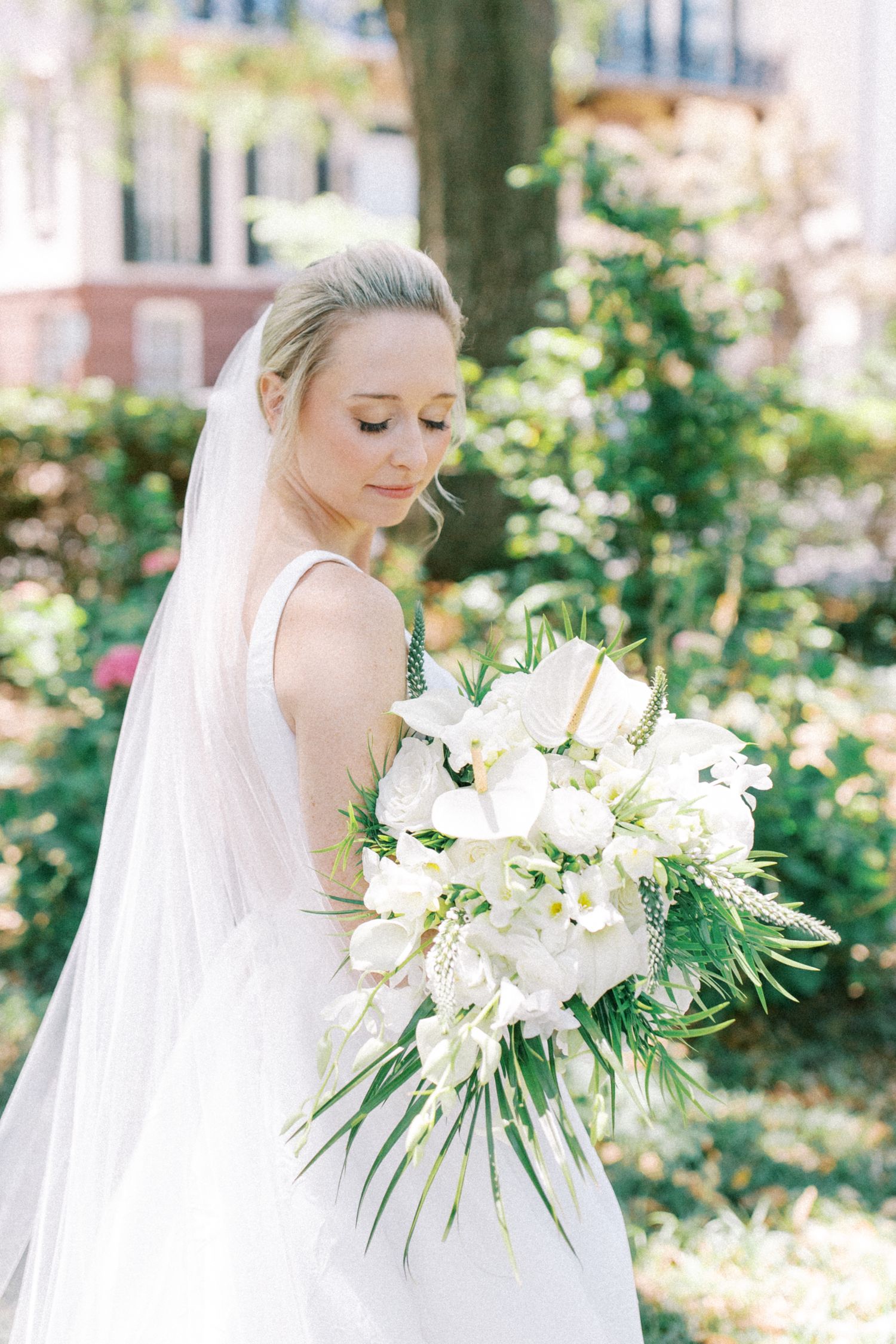 Elegant bridal portrait showcasing white floral bouquet in a garden setting.