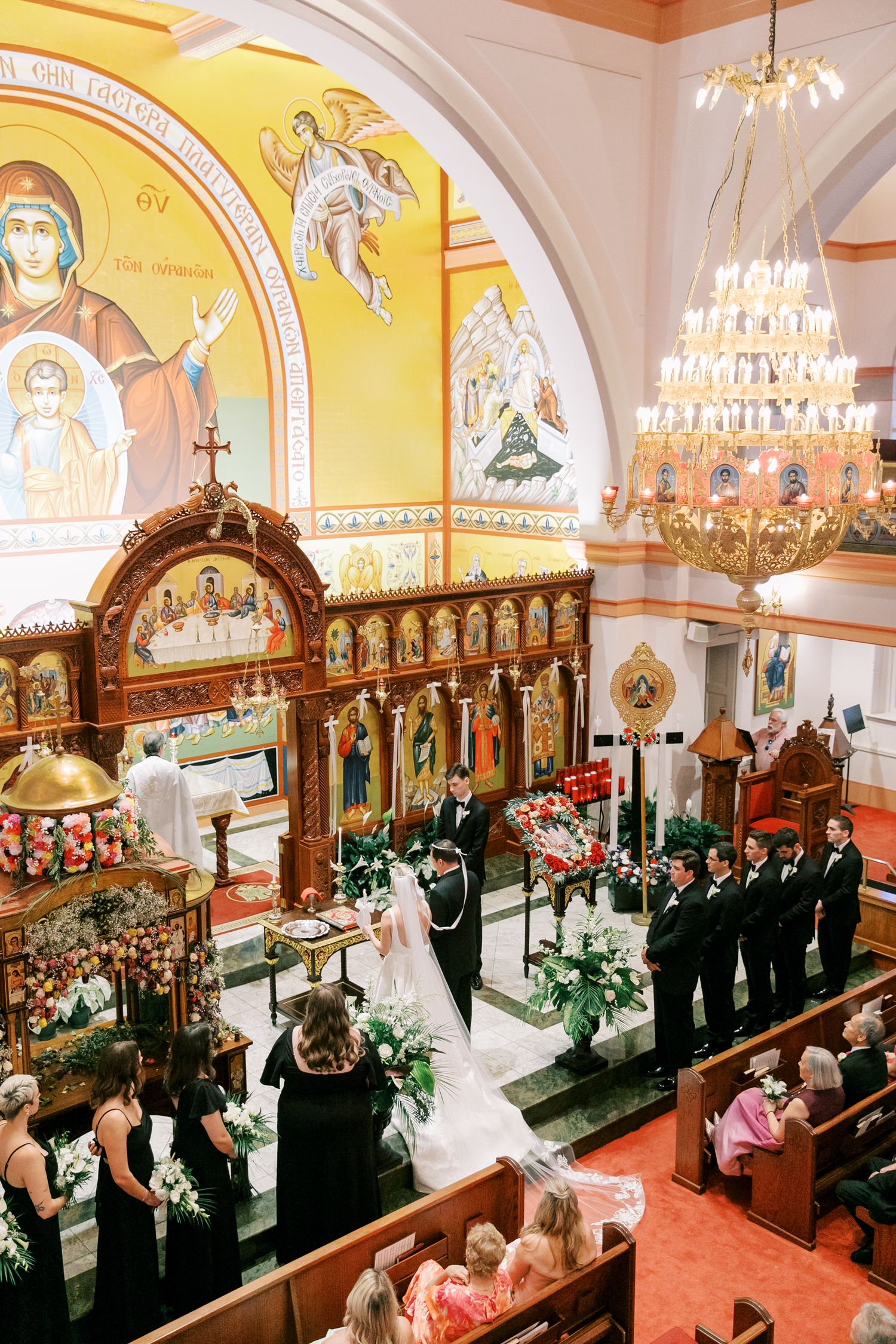 Ornate Orthodox church interior with golden icons and crystal chandelier during ceremony at St. Paul's Greek Orthodox Church.