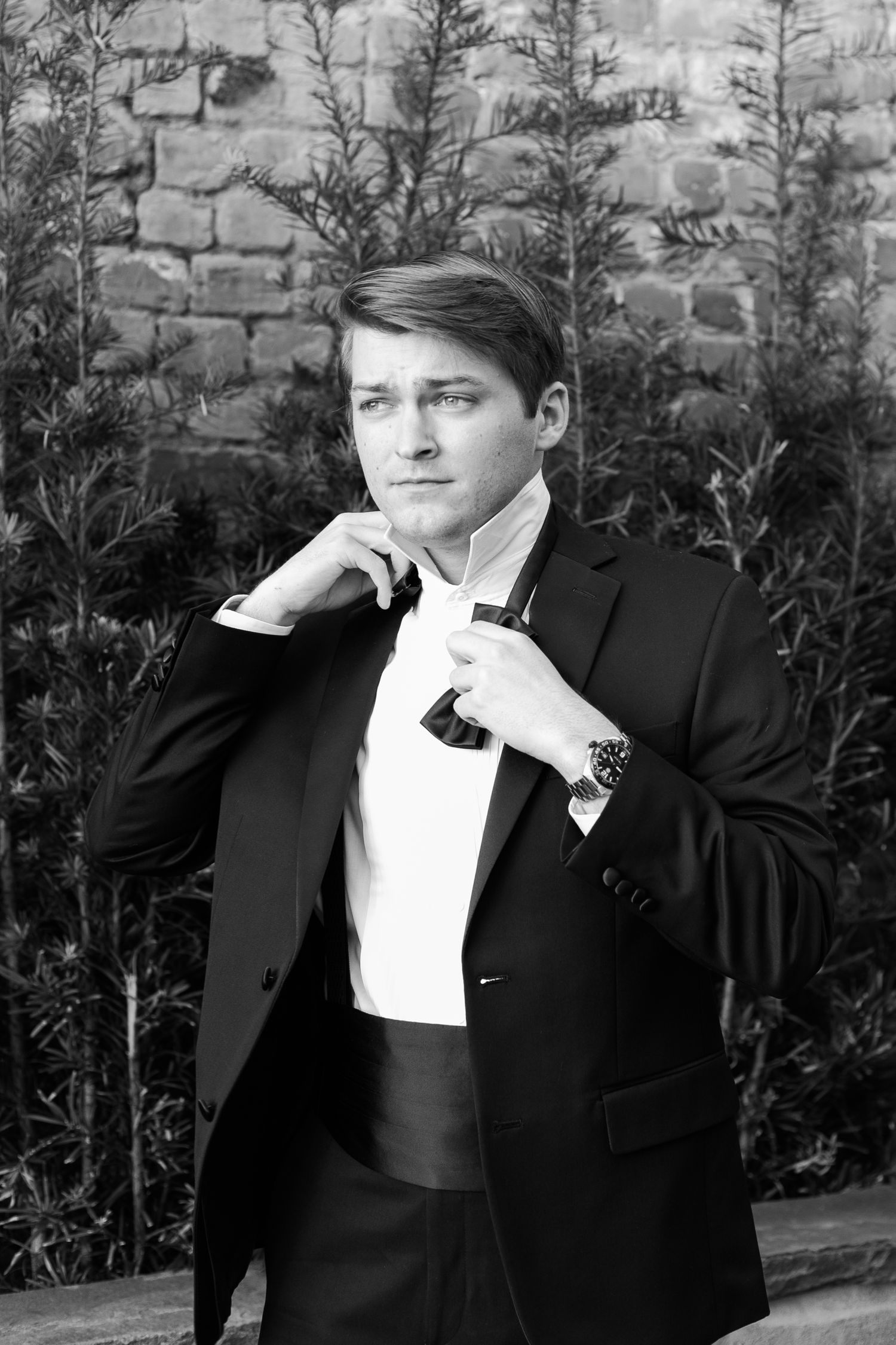 A sequence of black and white photos showing a man in a tuxedo adjusting his bowtie and collar.