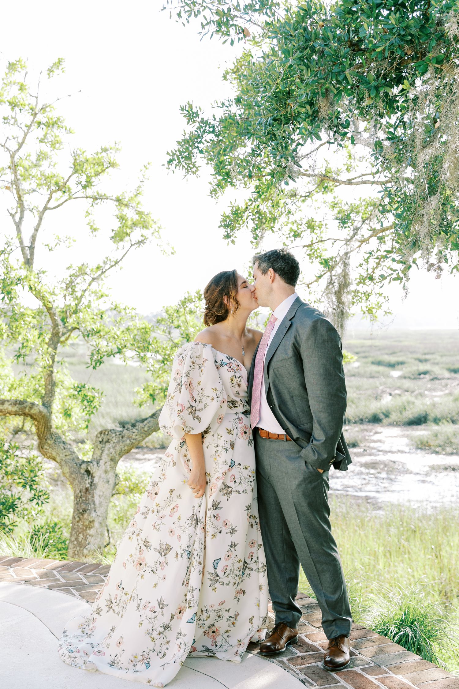 A romantic moment captured between a couple under a tree with a scenic landscape view.