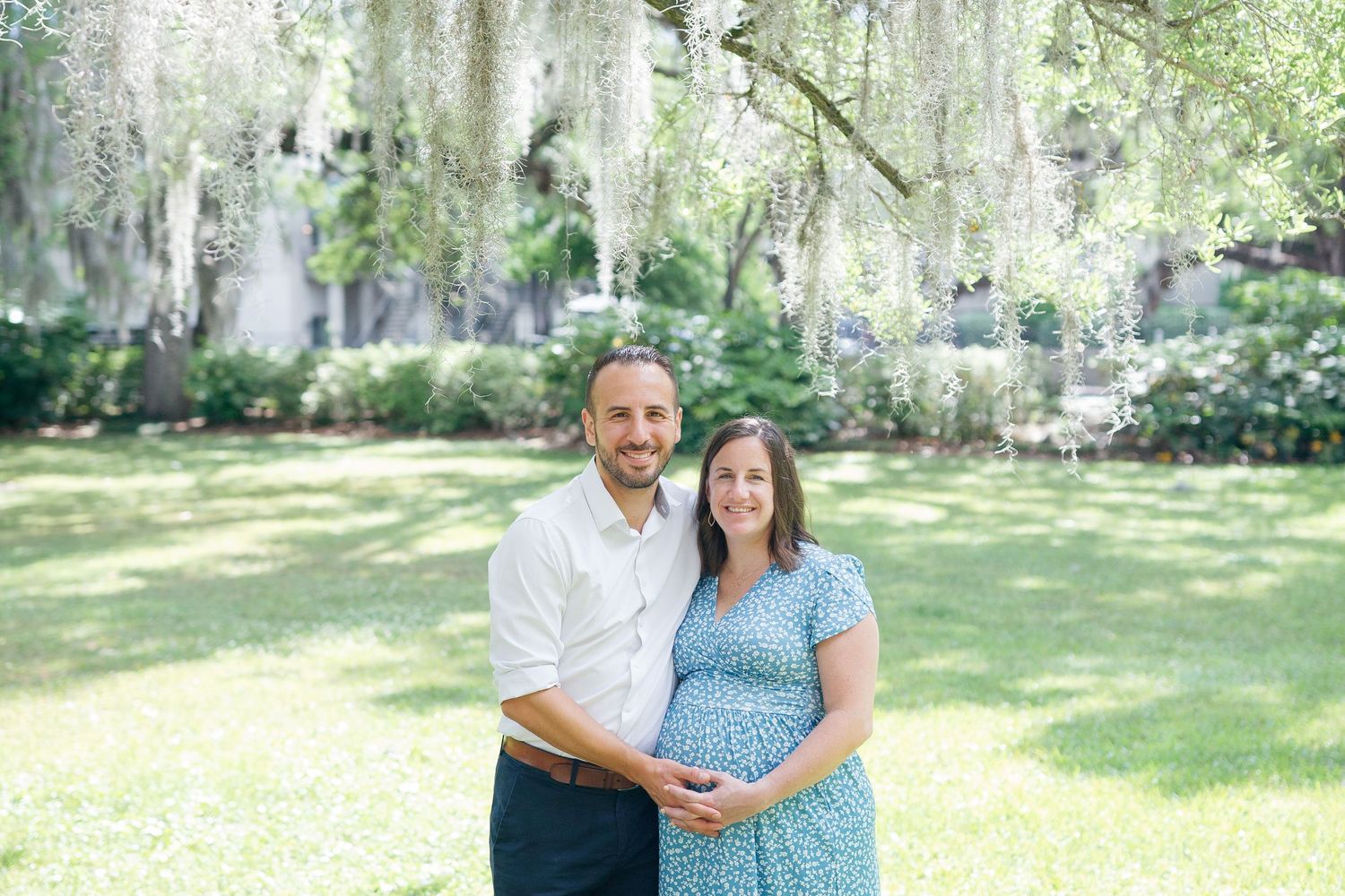 A romantic maternity session set in a dreamy garden with Spanish moss hanging overhead.