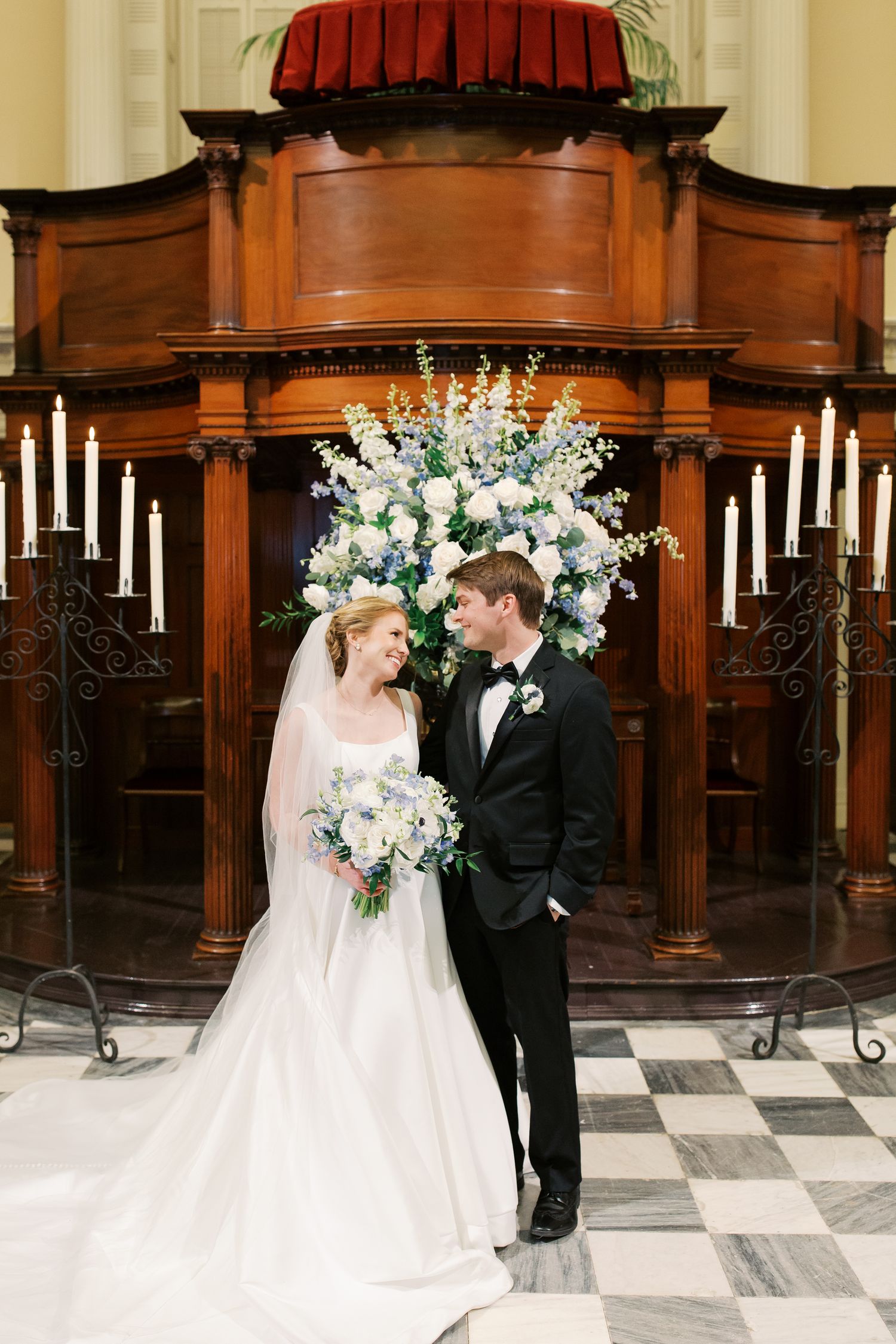 Elegant church altar decorated with white floral arrangements and candles for wedding ceremony.