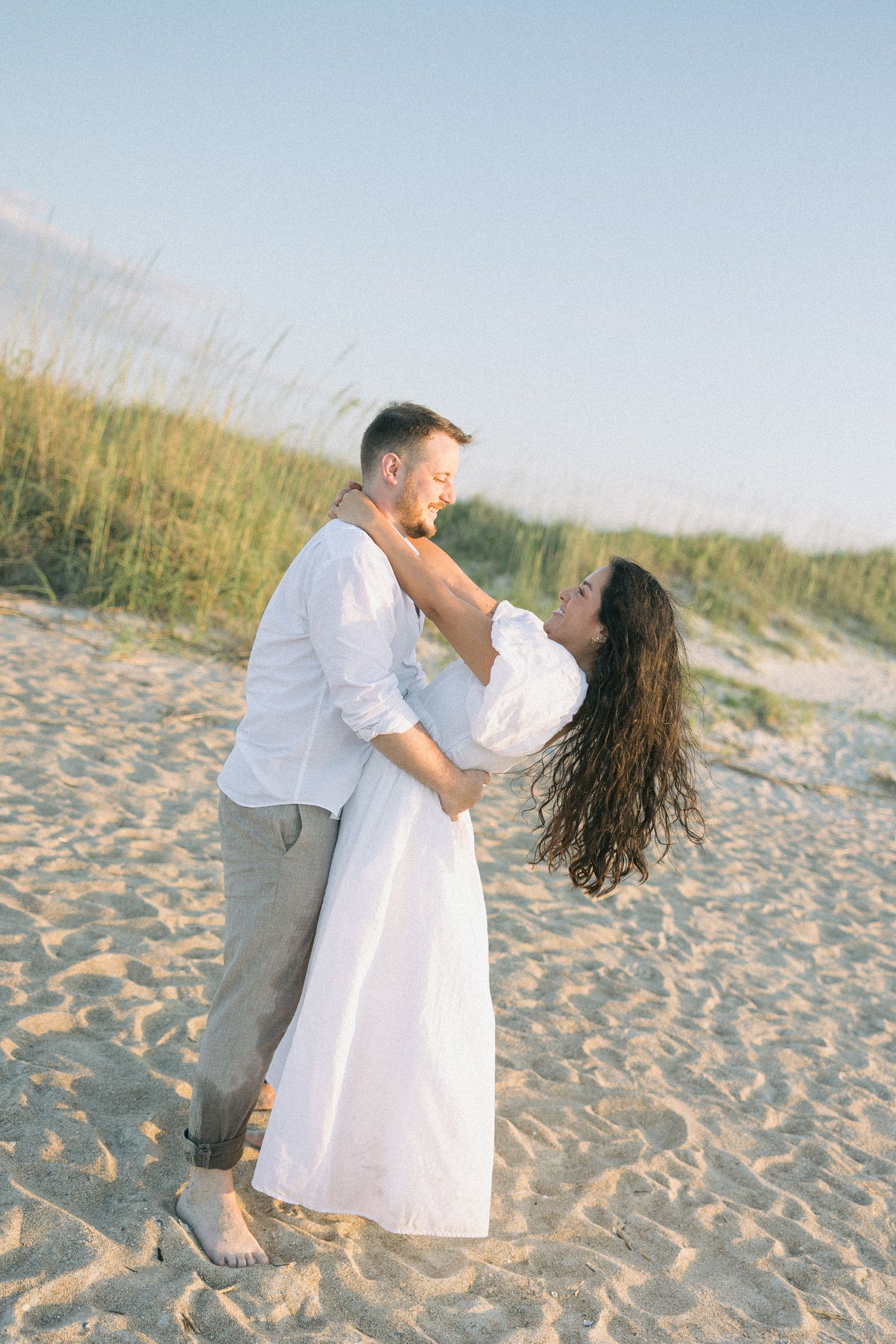 A romantic beach photoshoot sequence showing intimate moments on sandy dunes at golden hour.