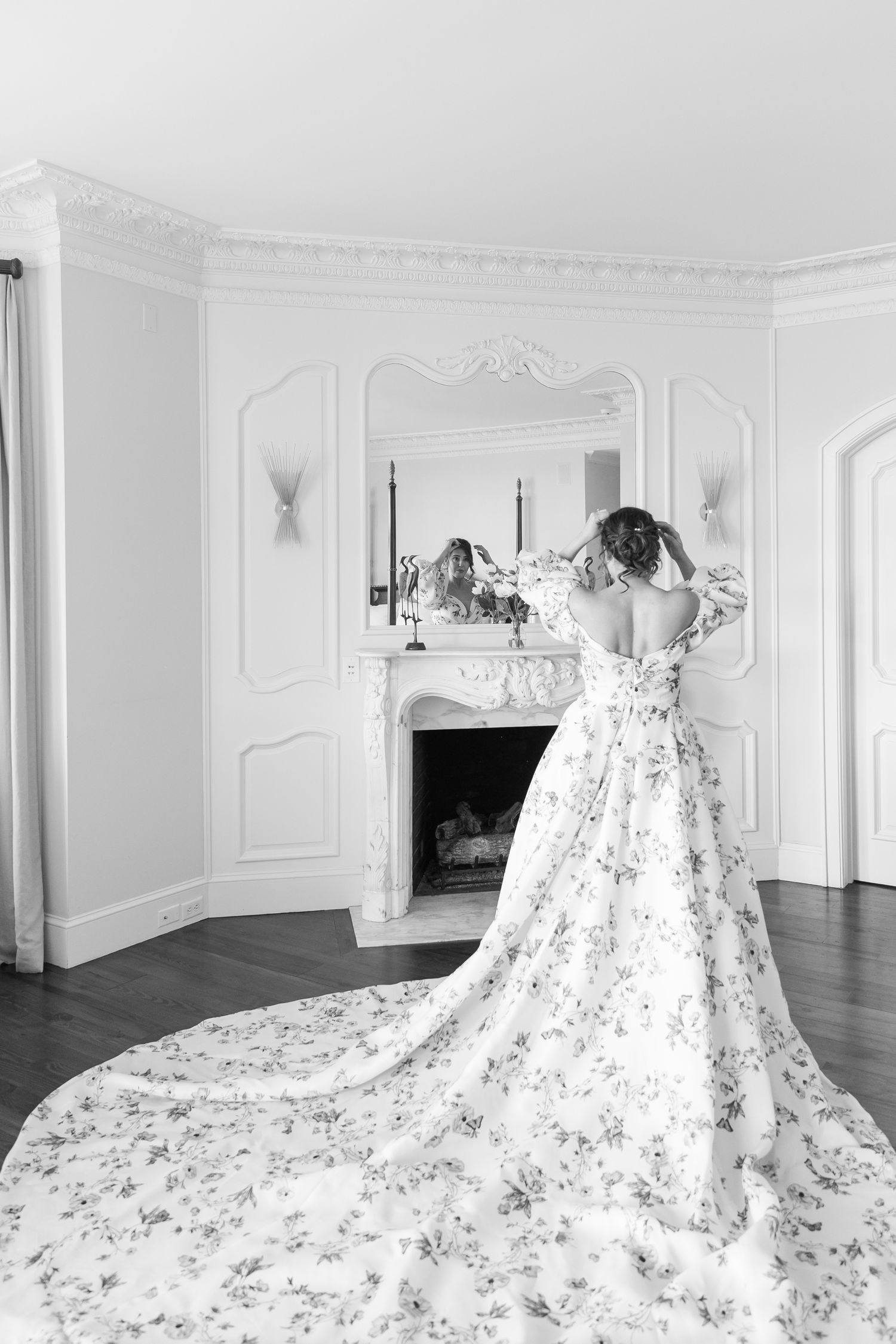 A dramatic white wedding gown with floral details and an extra-long cathedral train displayed in an elegant white room.