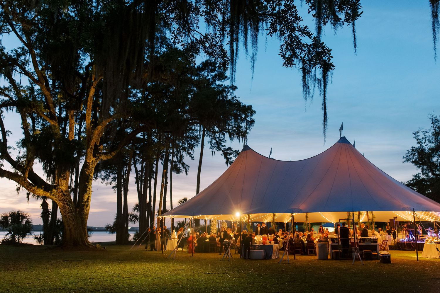 Evening wedding reception under illuminated tent with Spanish moss trees in background at 700 Wilmington.