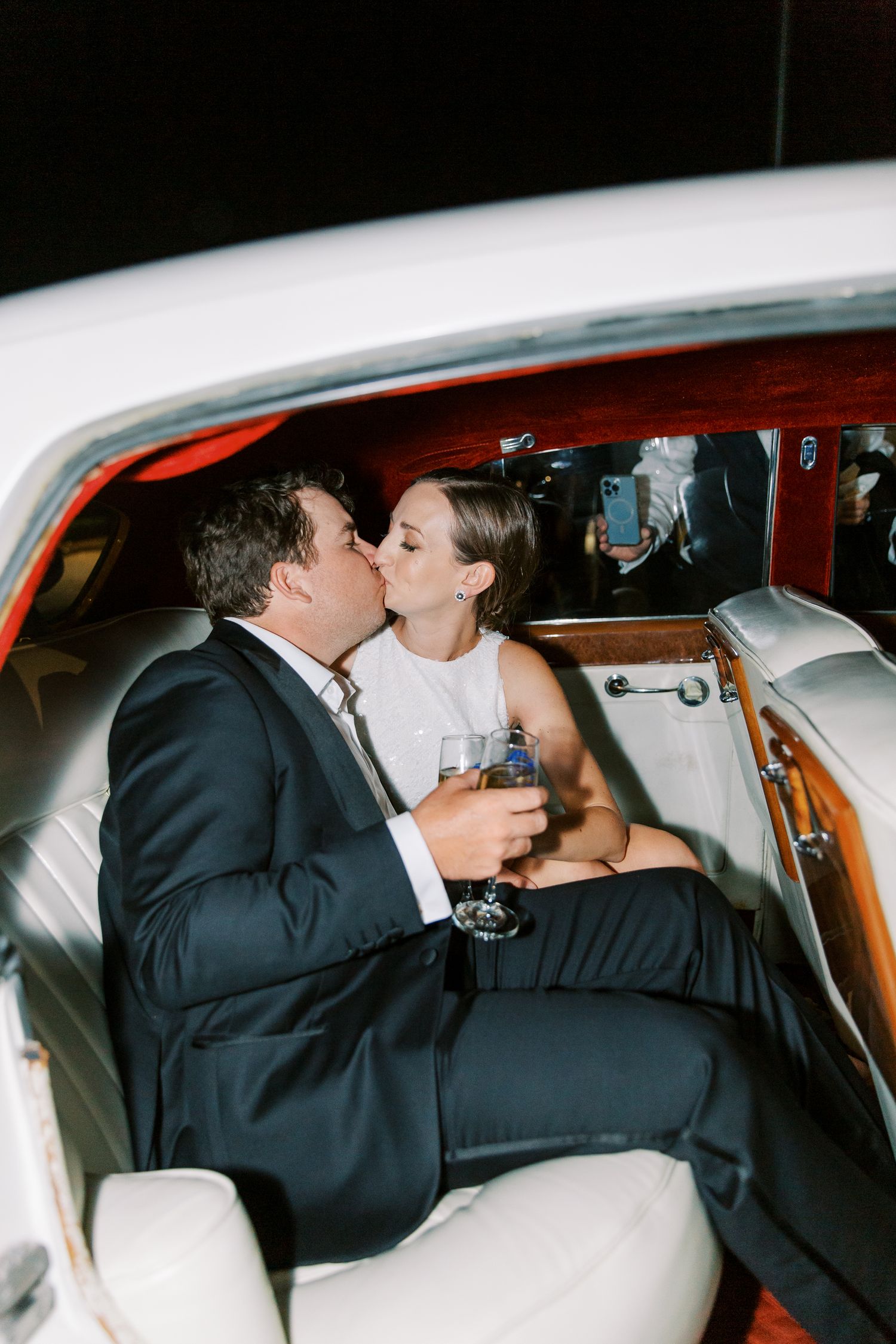 Romantic moment shared in vintage car backseat during wedding celebration.