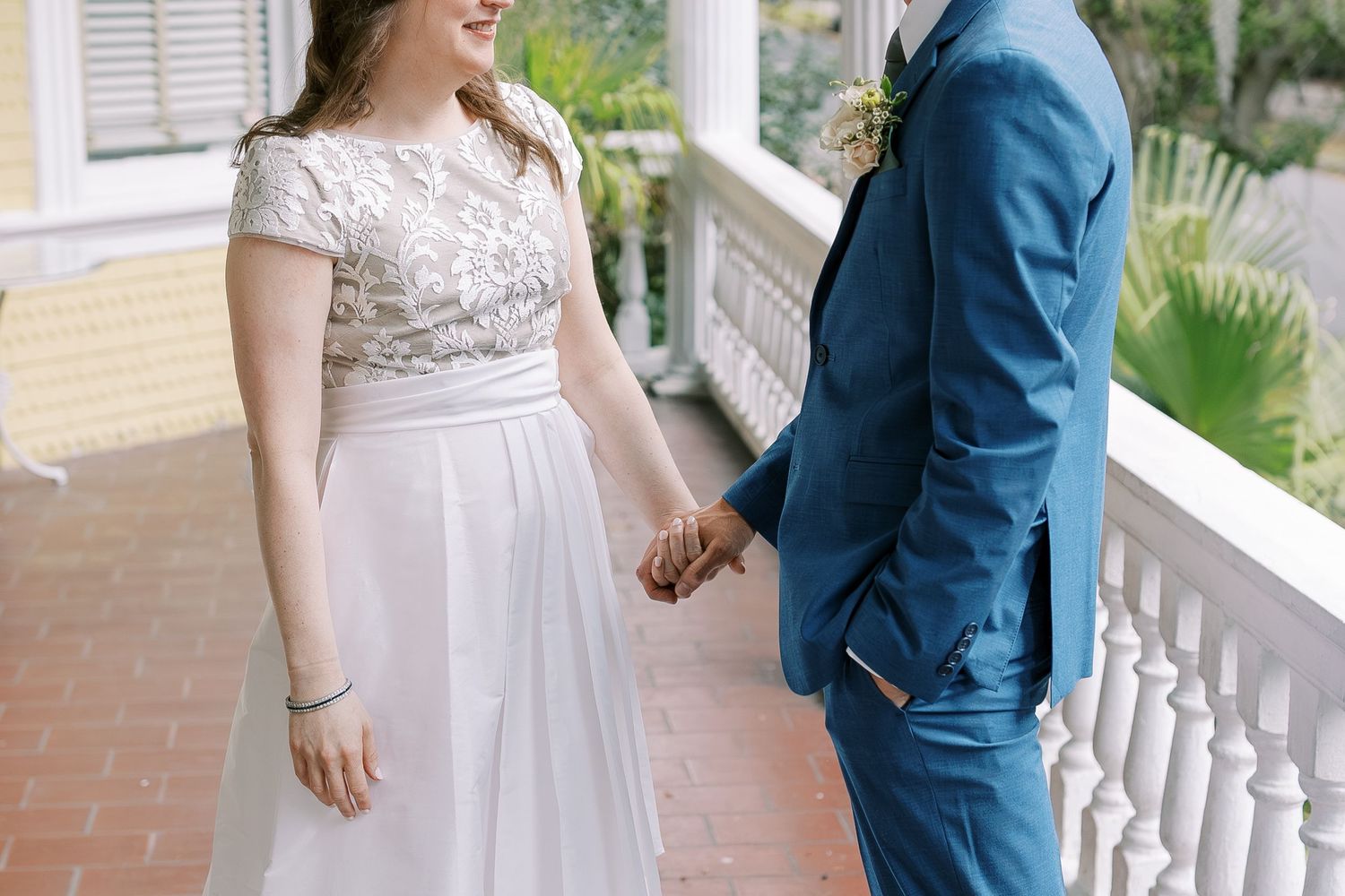 Couple sharing a joyful moment on a sunlit porch during their wedding day.