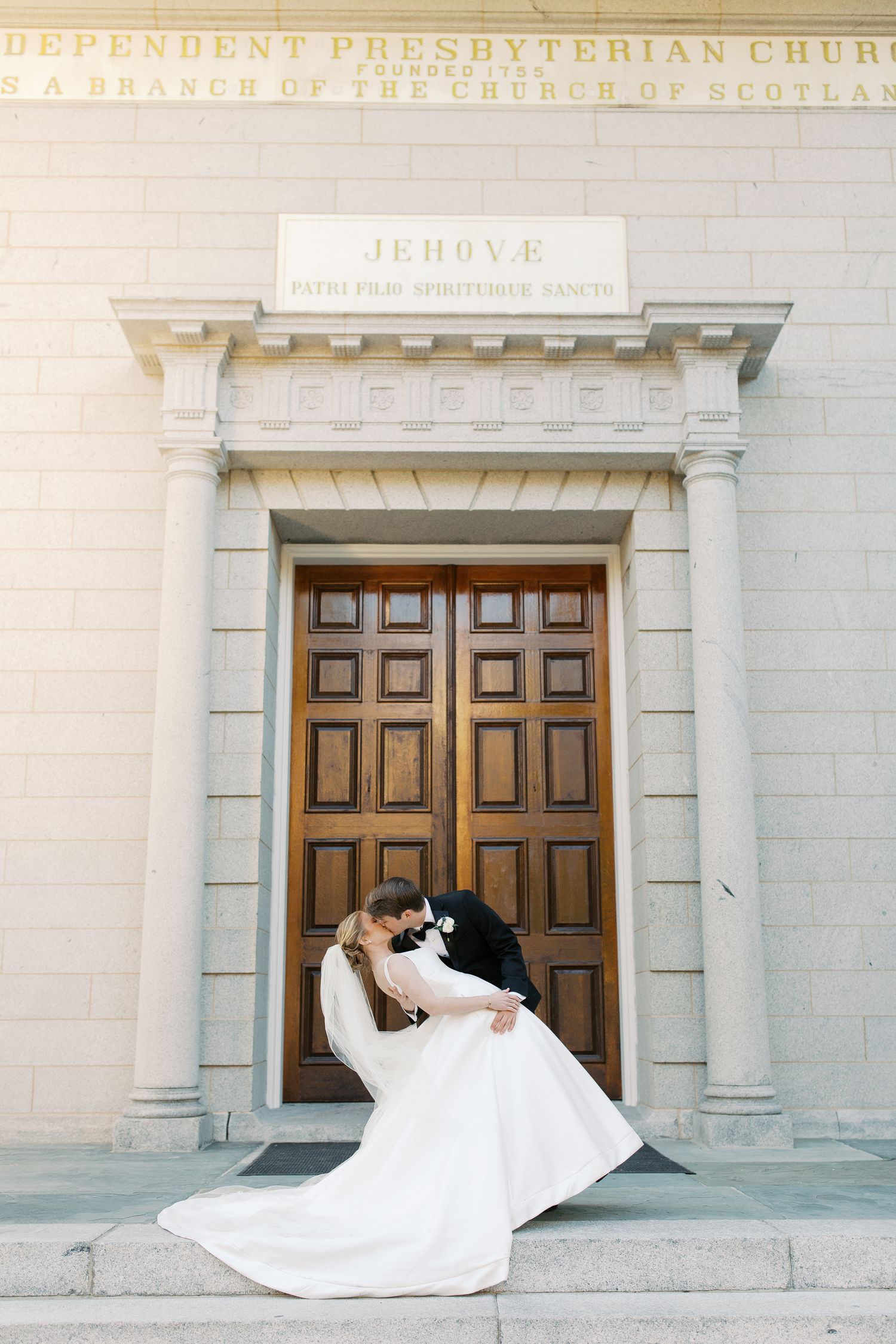 Wedding dress flowing dramatically in front of Presbyterian church doors.