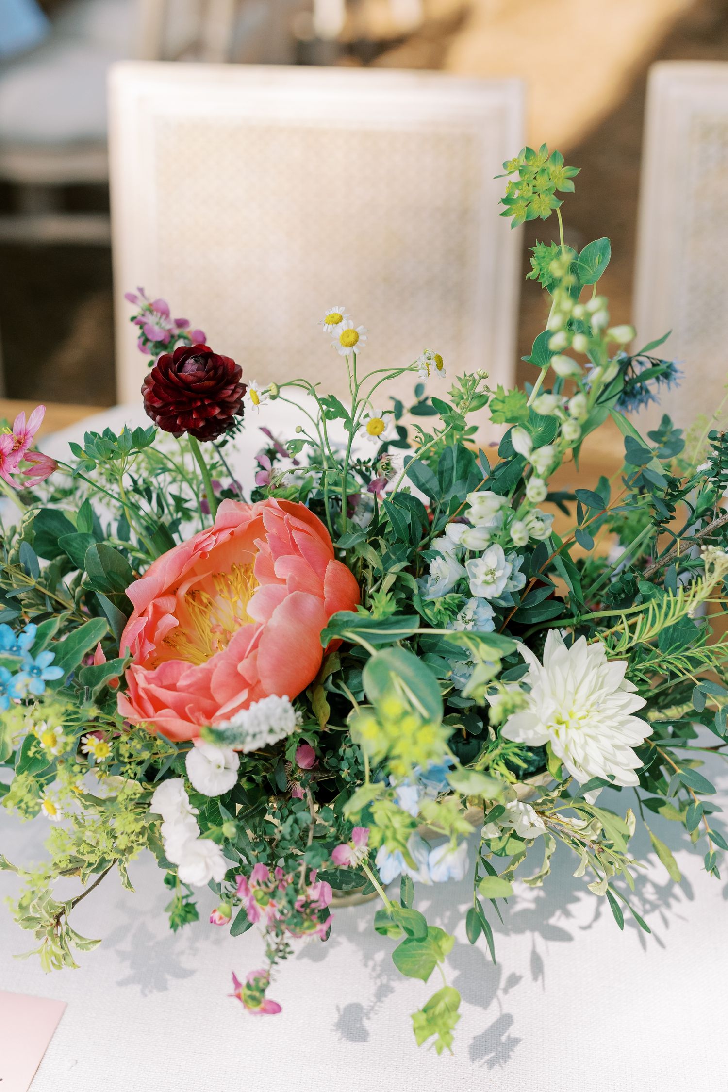 Close-up of a romantic garden-style floral arrangement featuring coral peonies and deep red roses.