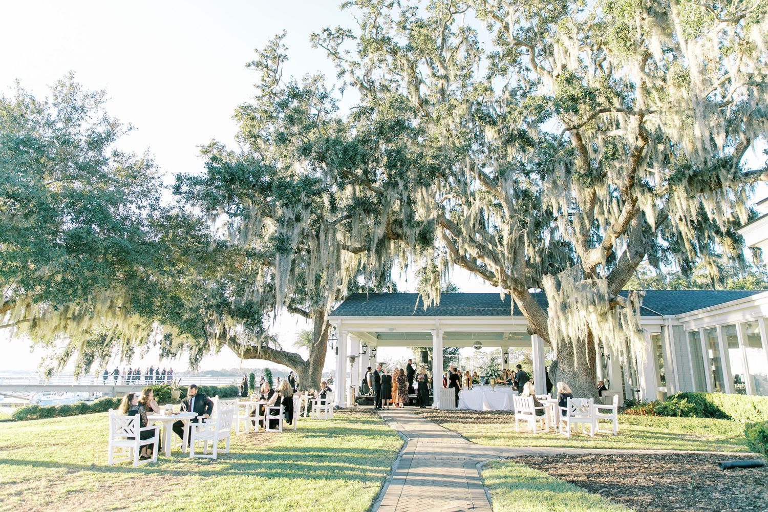 Outdoor wedding ceremony setup with white pavilion under moss-draped oak trees.