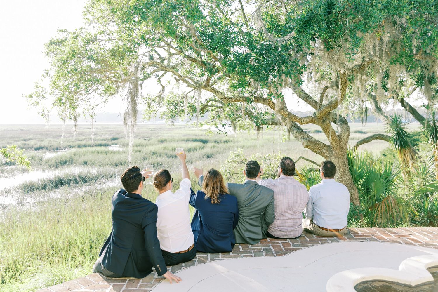 Row of guests sitting on benches overlooking a scenic coastal view.