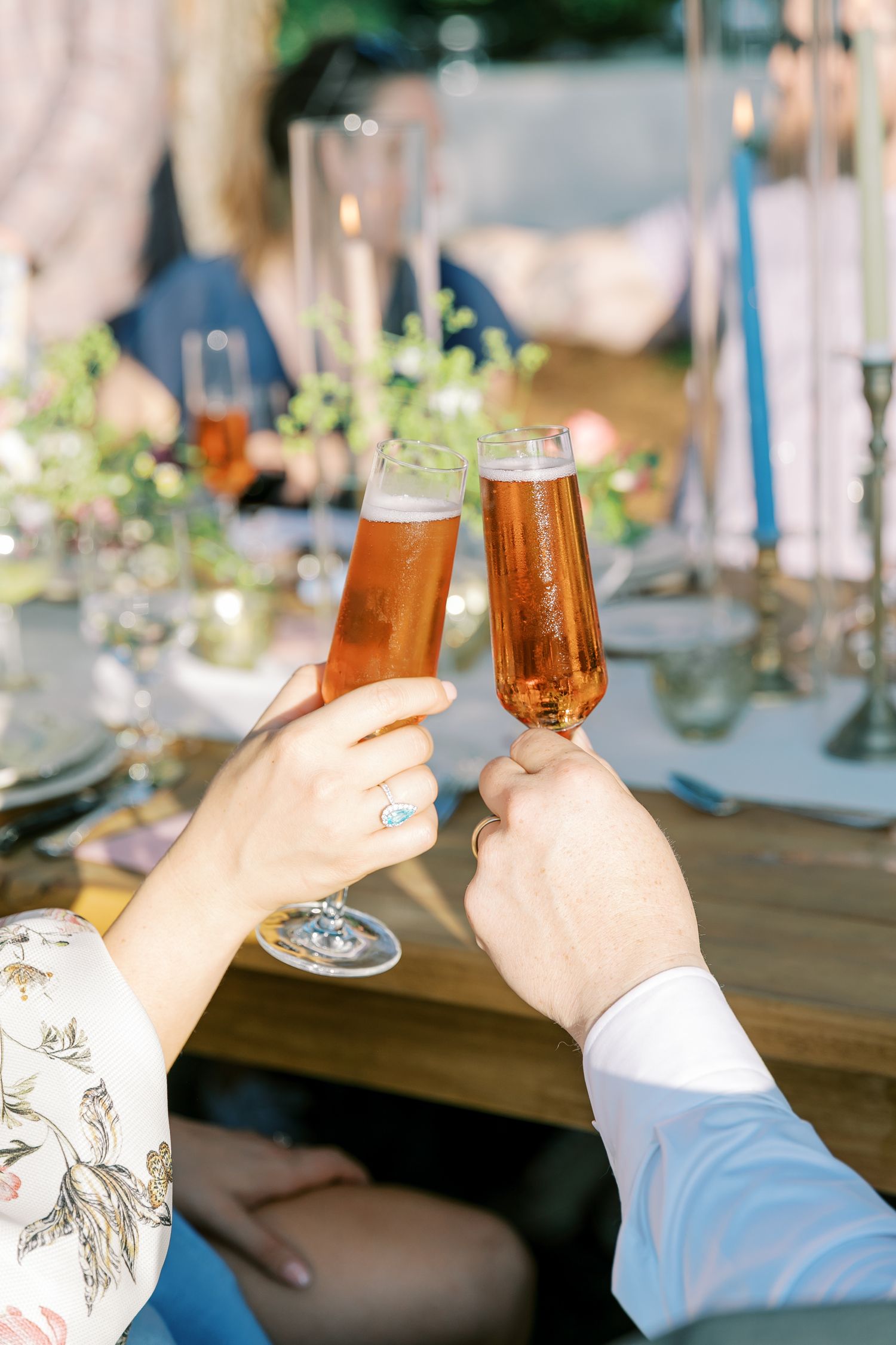 Hands raise glasses filled with amber-colored drinks for a celebratory toast.