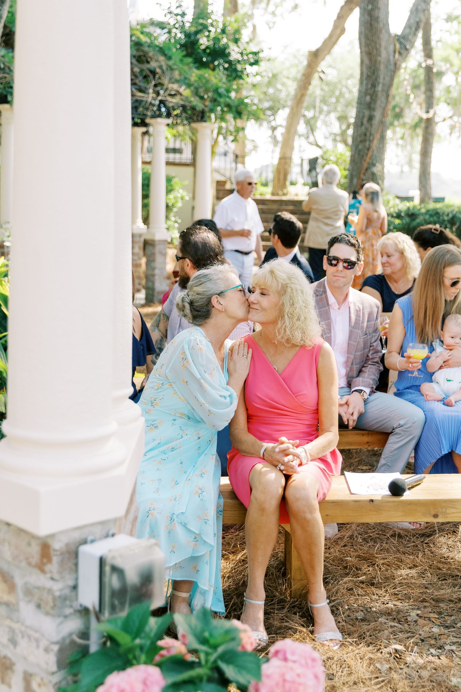 Group of guests relaxing on outdoor benches during a sunny garden event.
