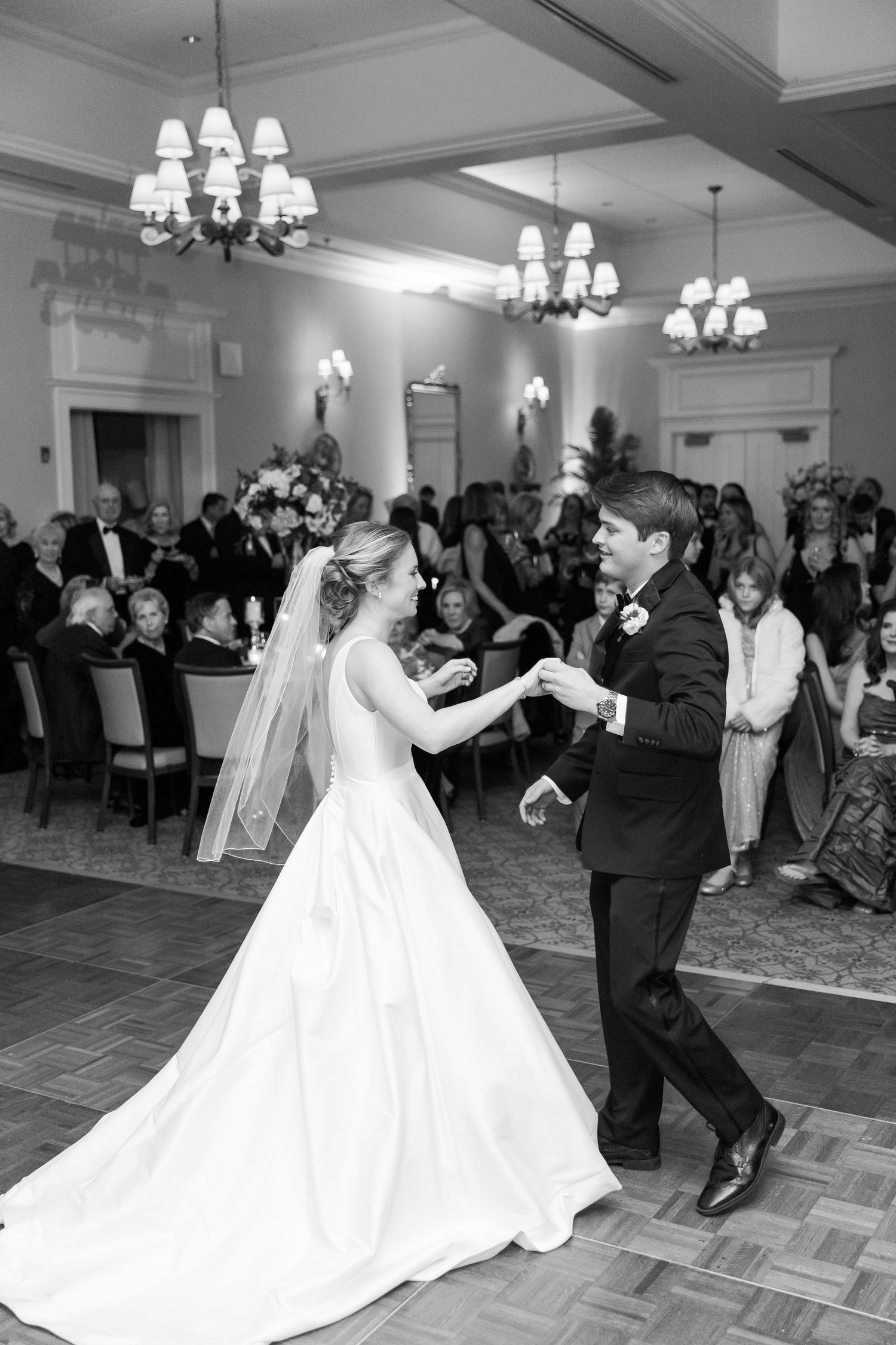 Wedding reception dance floor filled with guests celebrating as couple dances in white gown.