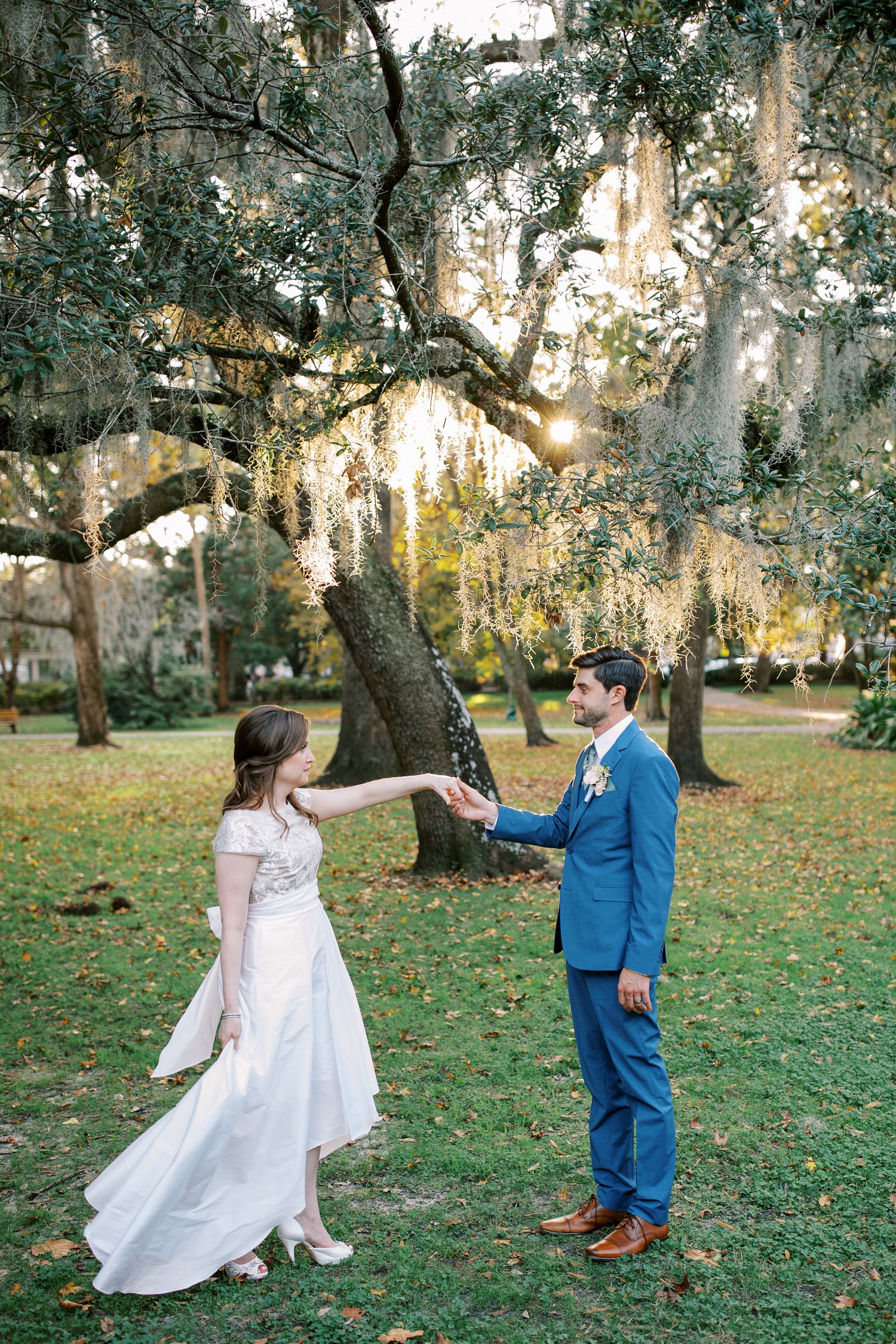 A playful dancing moment under moss-draped trees in a Southern garden.