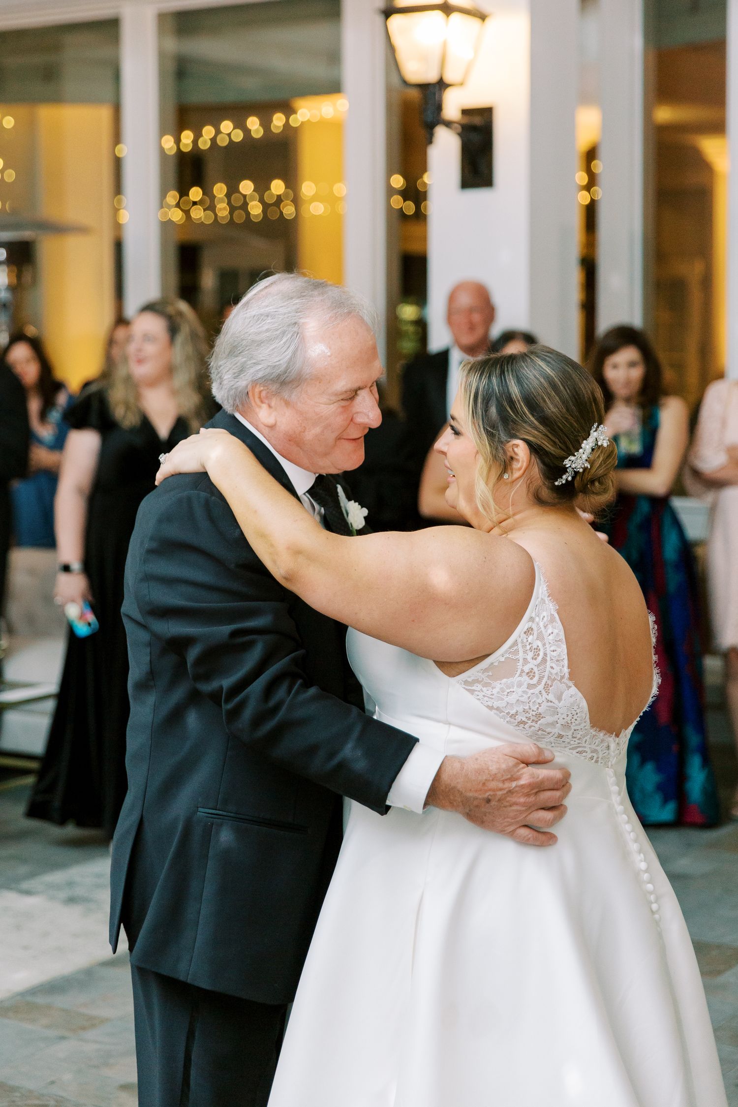 A heartwarming dance moment at a wedding reception under warm patio lighting.