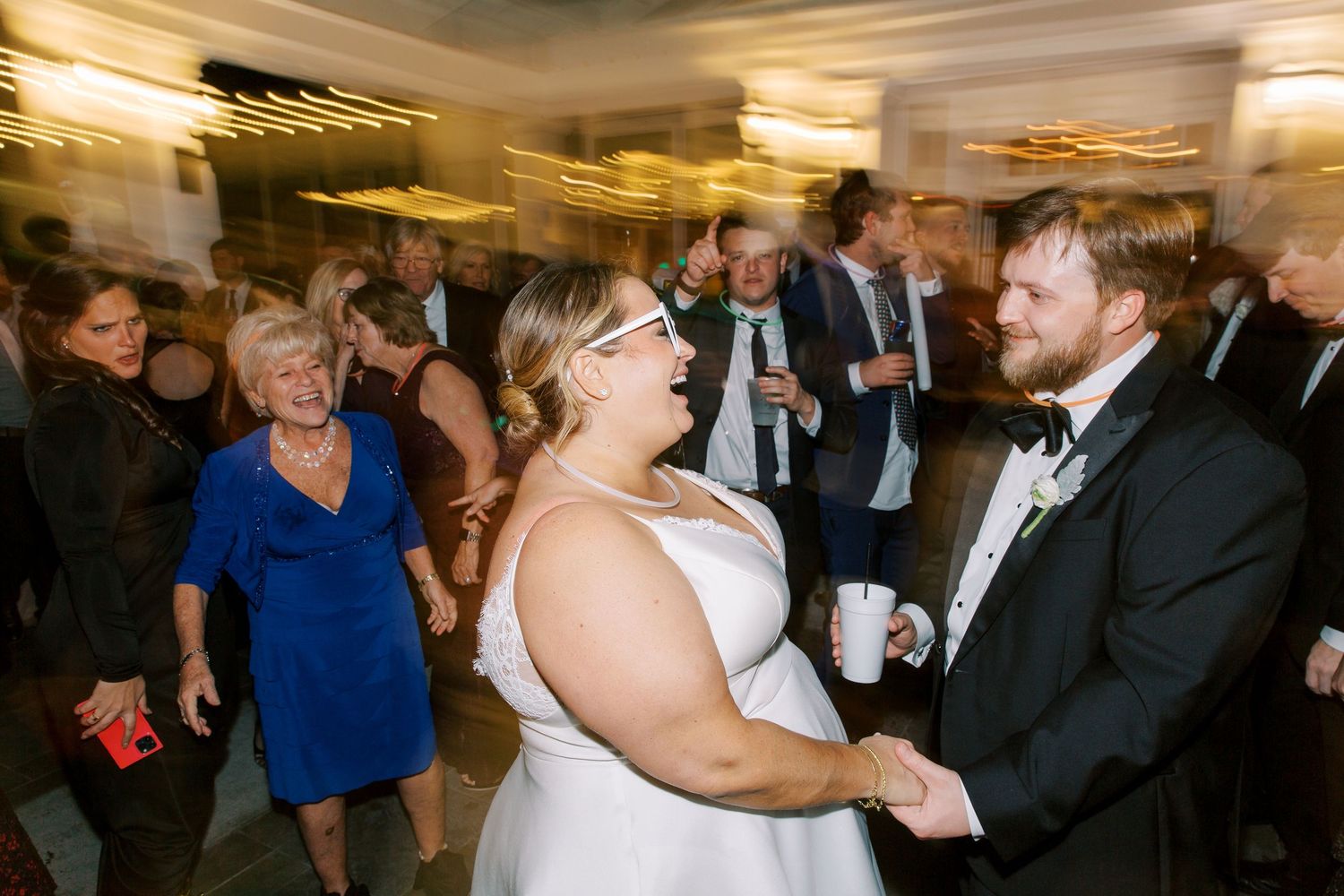 Wedding reception dance floor with guests celebrating in motion-blurred festive atmosphere.