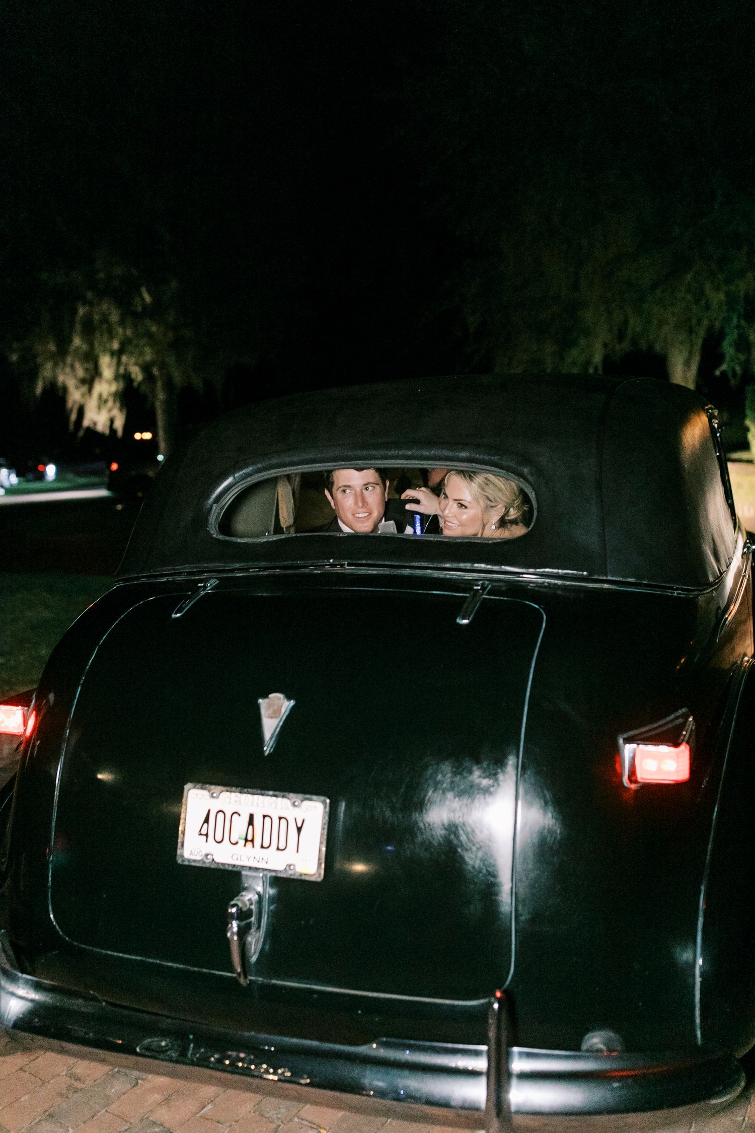 Nighttime vintage car photo with backseat view through rear window.