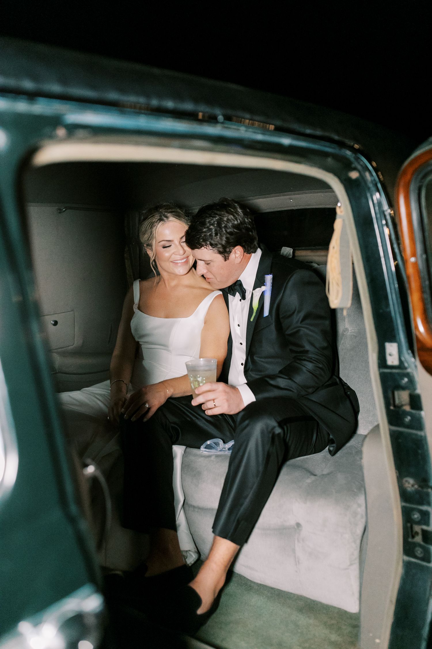 Intimate moment captured inside a vintage car with formal wedding attire.