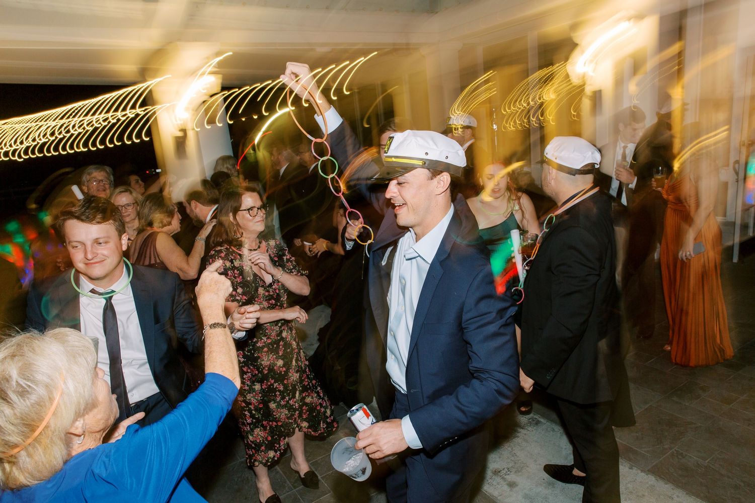 Lively wedding reception dance party with guests celebrating under string lights.