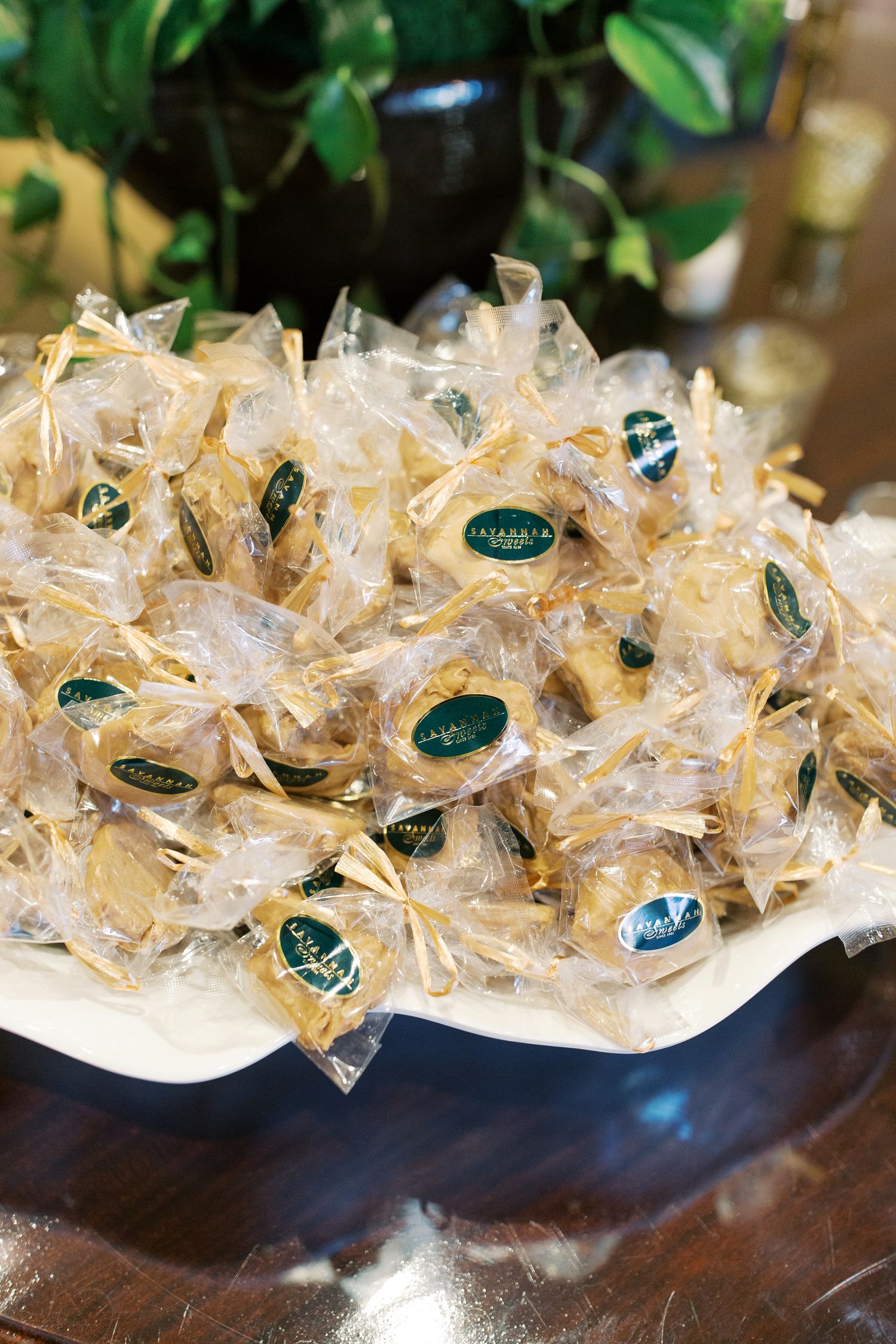 Wedding favors wrapped in delicate white tulle with green labels arranged in a decorative display.