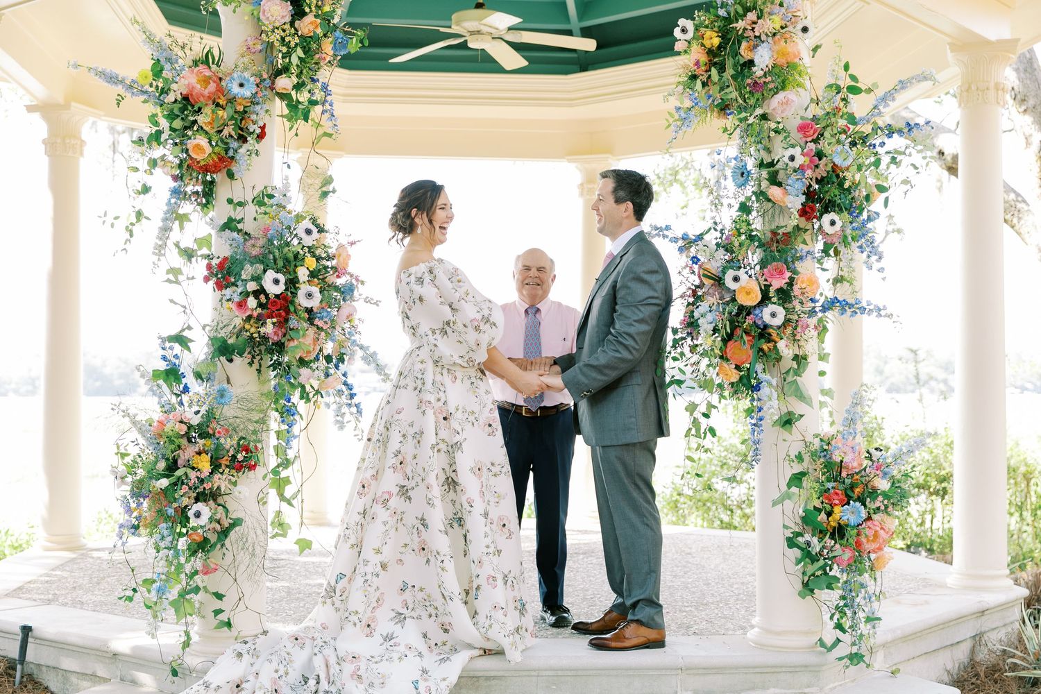 Wedding ceremony under flower-adorned gazebo with florals and greenery creating romantic archway.