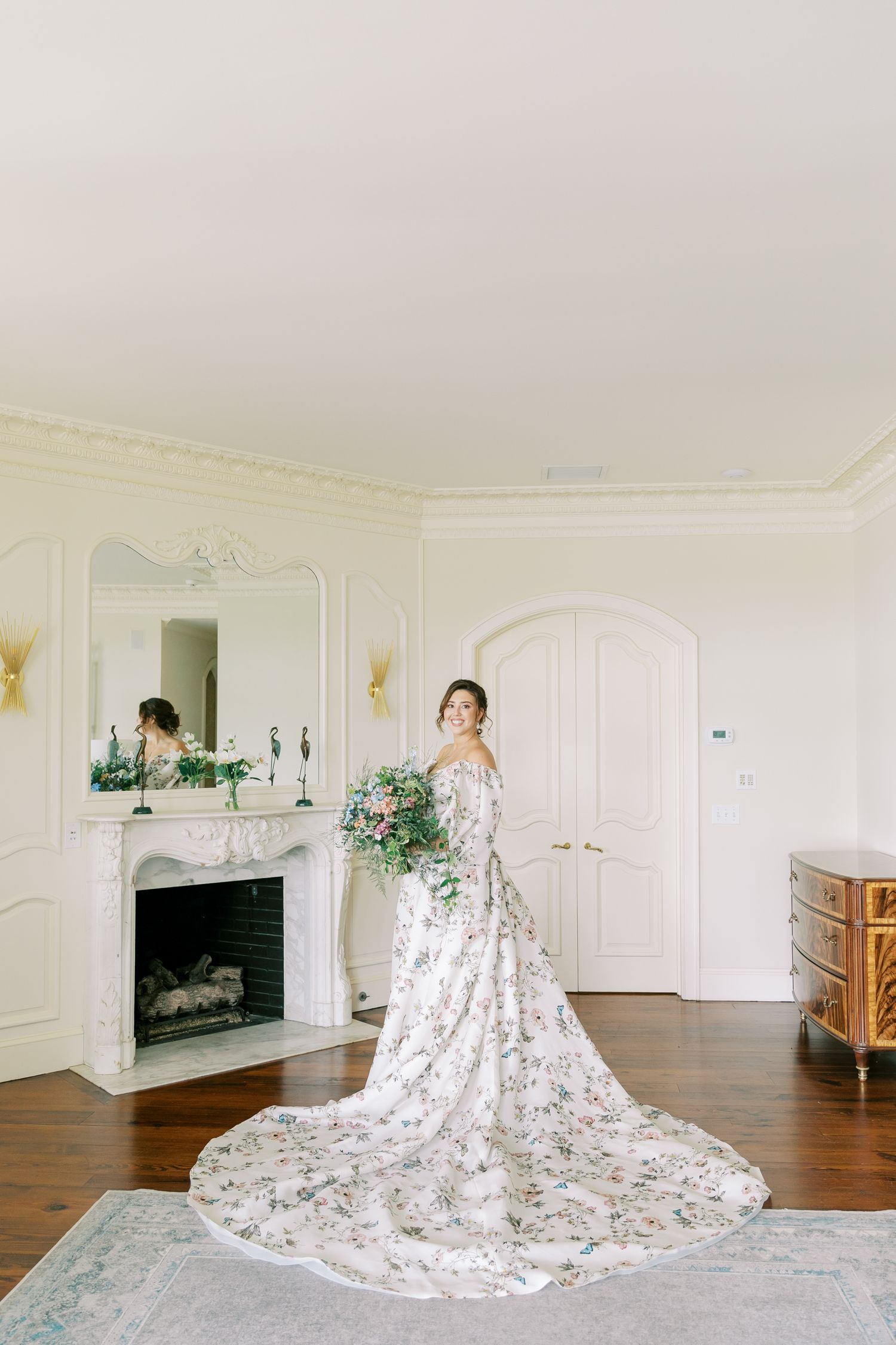 Four images showing a long floral wedding dress with a dramatic train displayed in a bright white room.