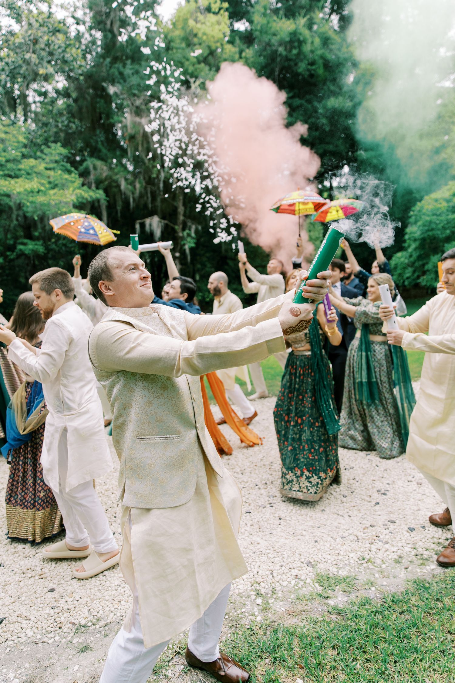 Celebratory moment with colorful smoke and parasols at an outdoor wedding celebration.