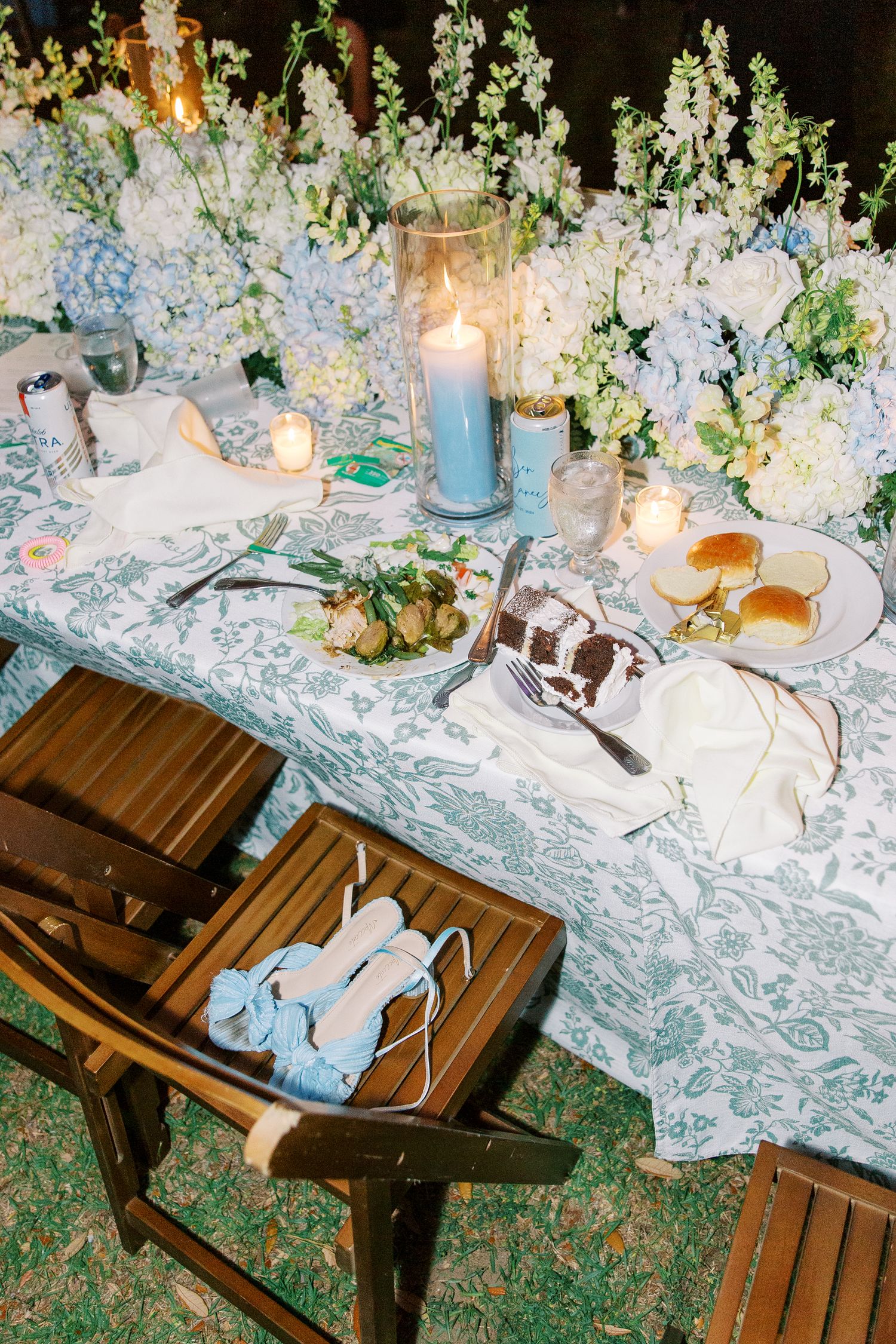 Wedding reception table with blue and white floral arrangements, candles, and place settings.