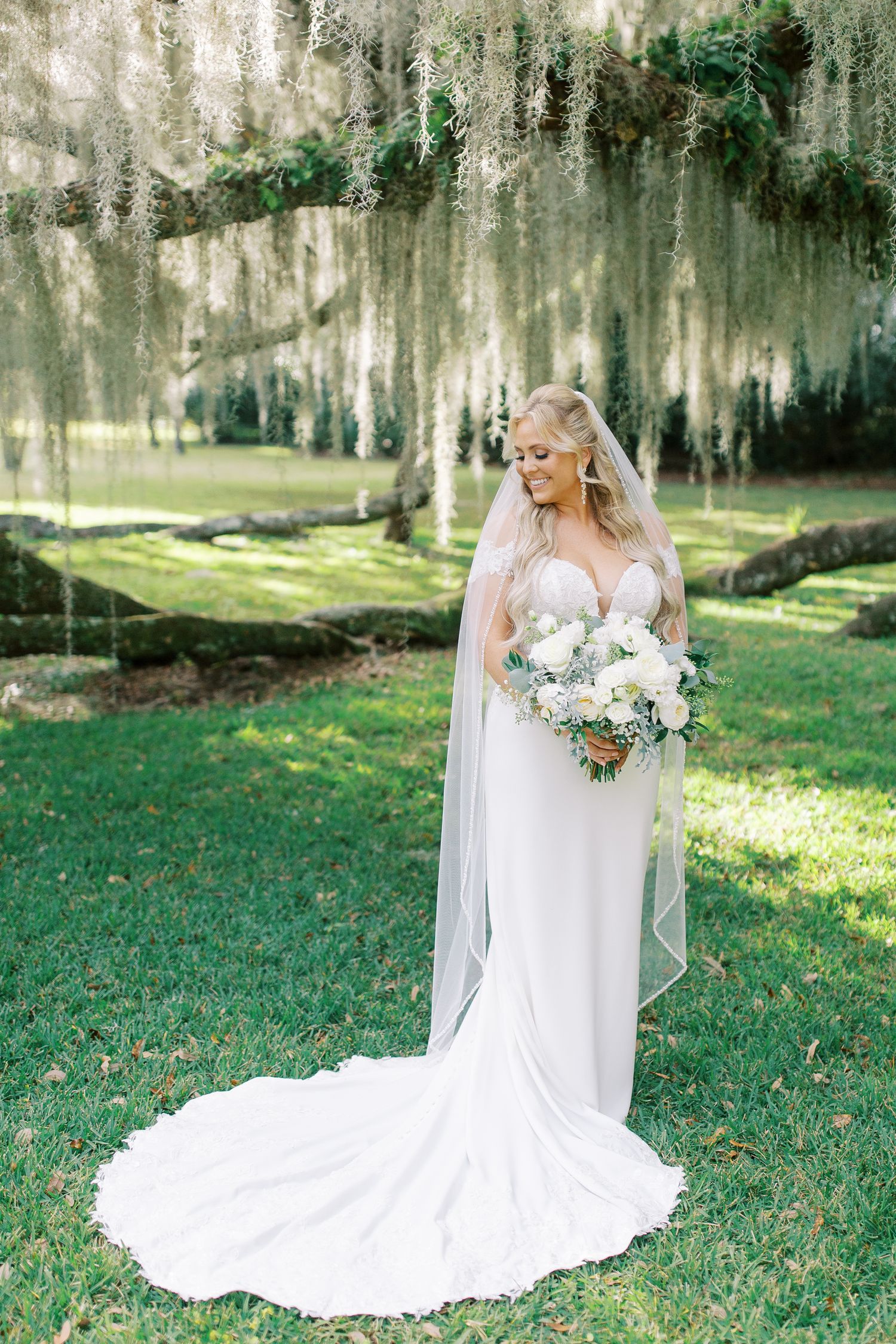 Elegant bridal portrait under Spanish moss trees with white floral bouquet at Beaulieau.