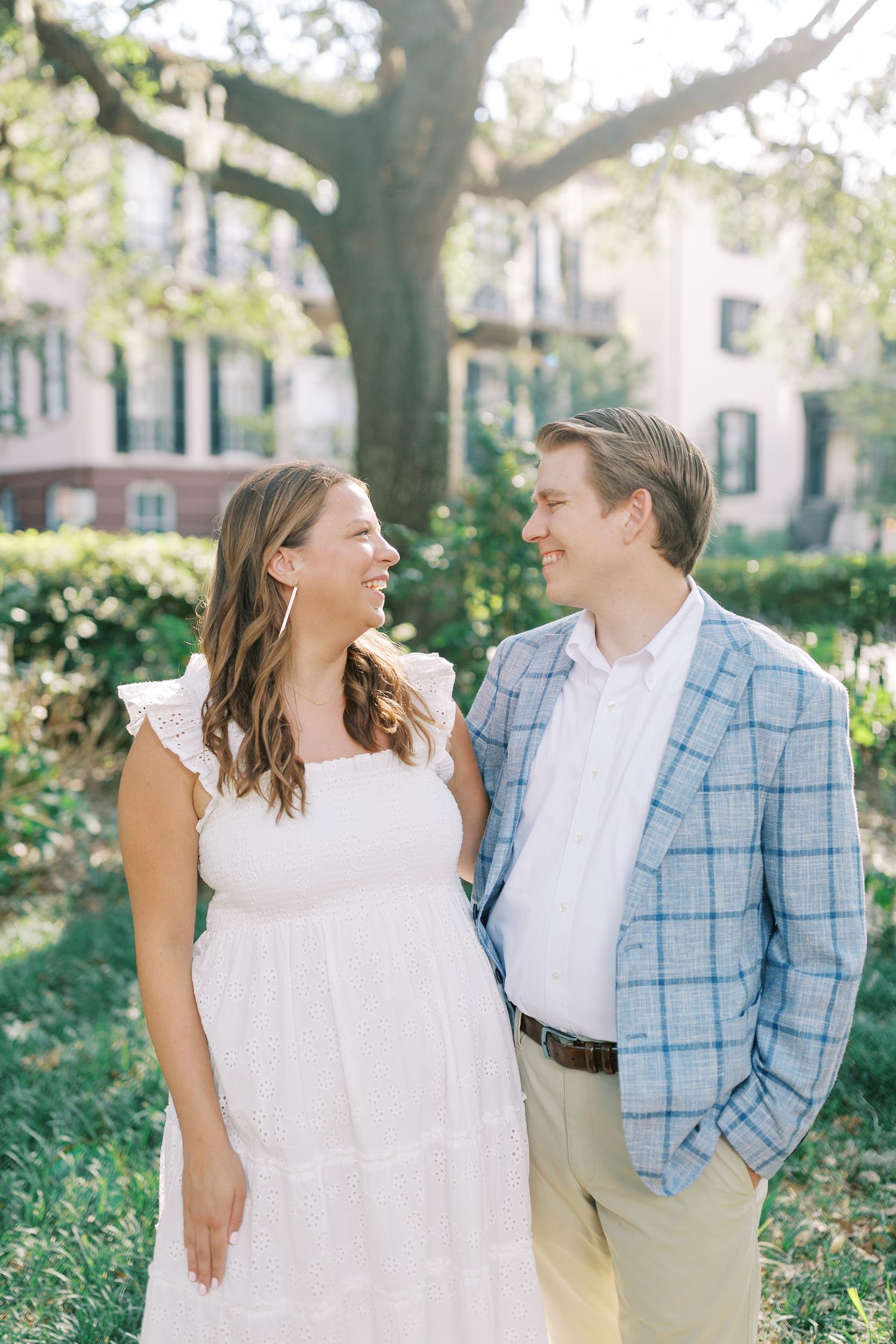 Casual engagement photo of laughing couple in garden setting in Monterey Square.