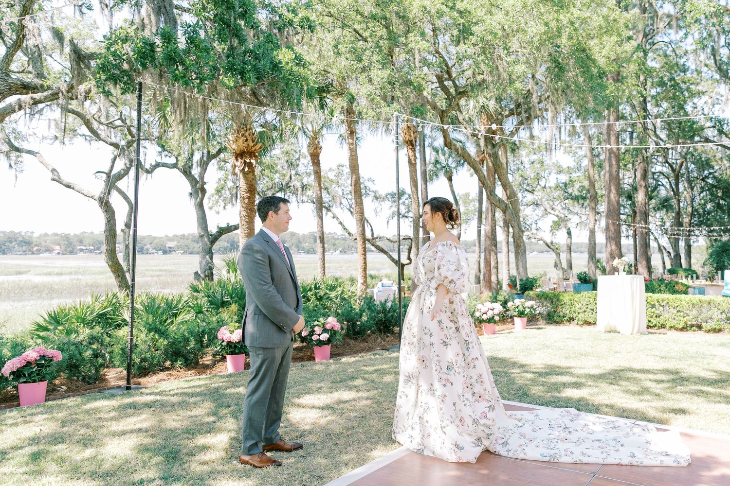 Two people share an intimate moment under Spanish moss-draped trees at an elegant outdoor wedding ceremony.