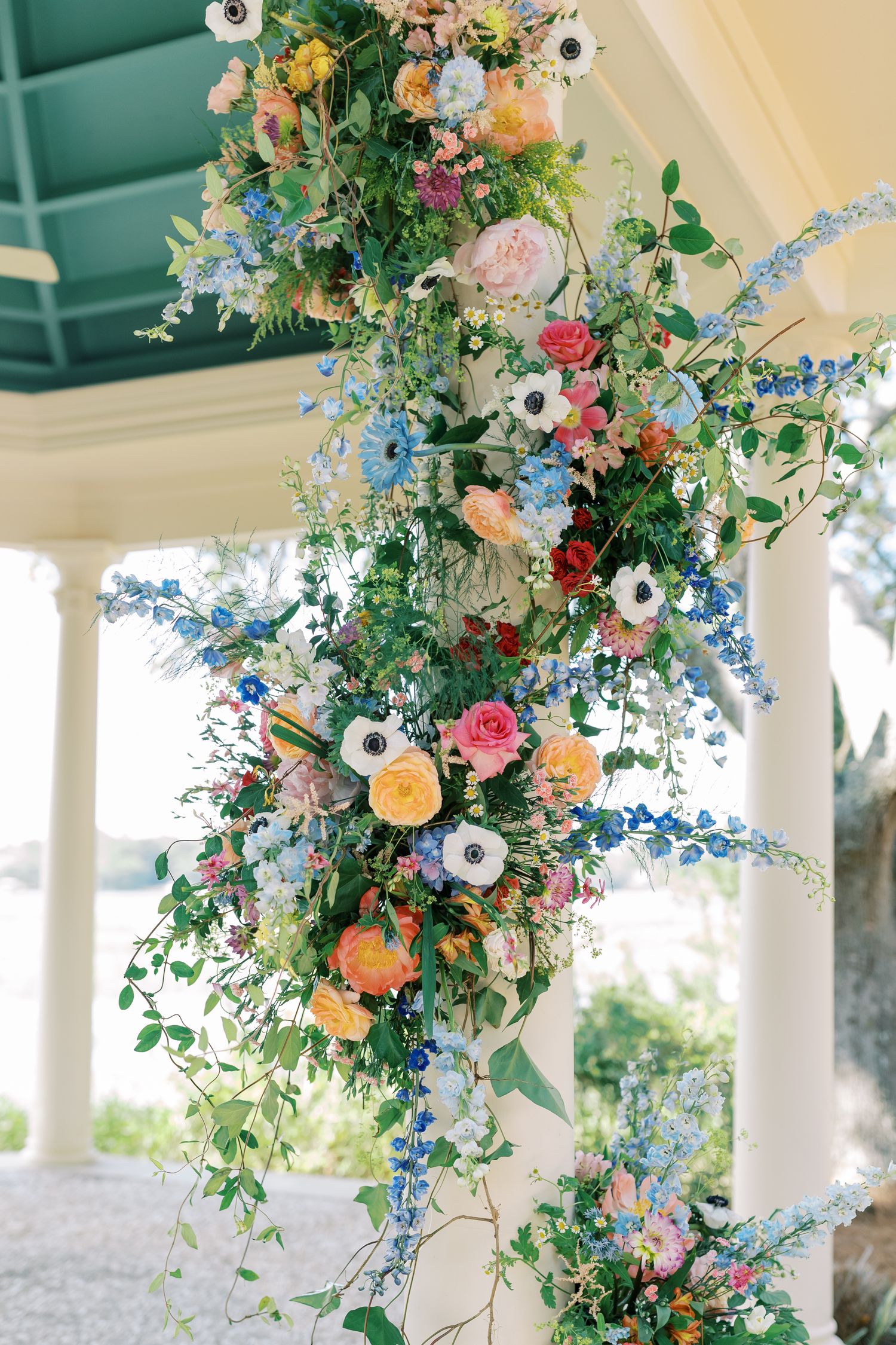Cascading floral installation with colorful blooms and greenery hanging from ceiling.