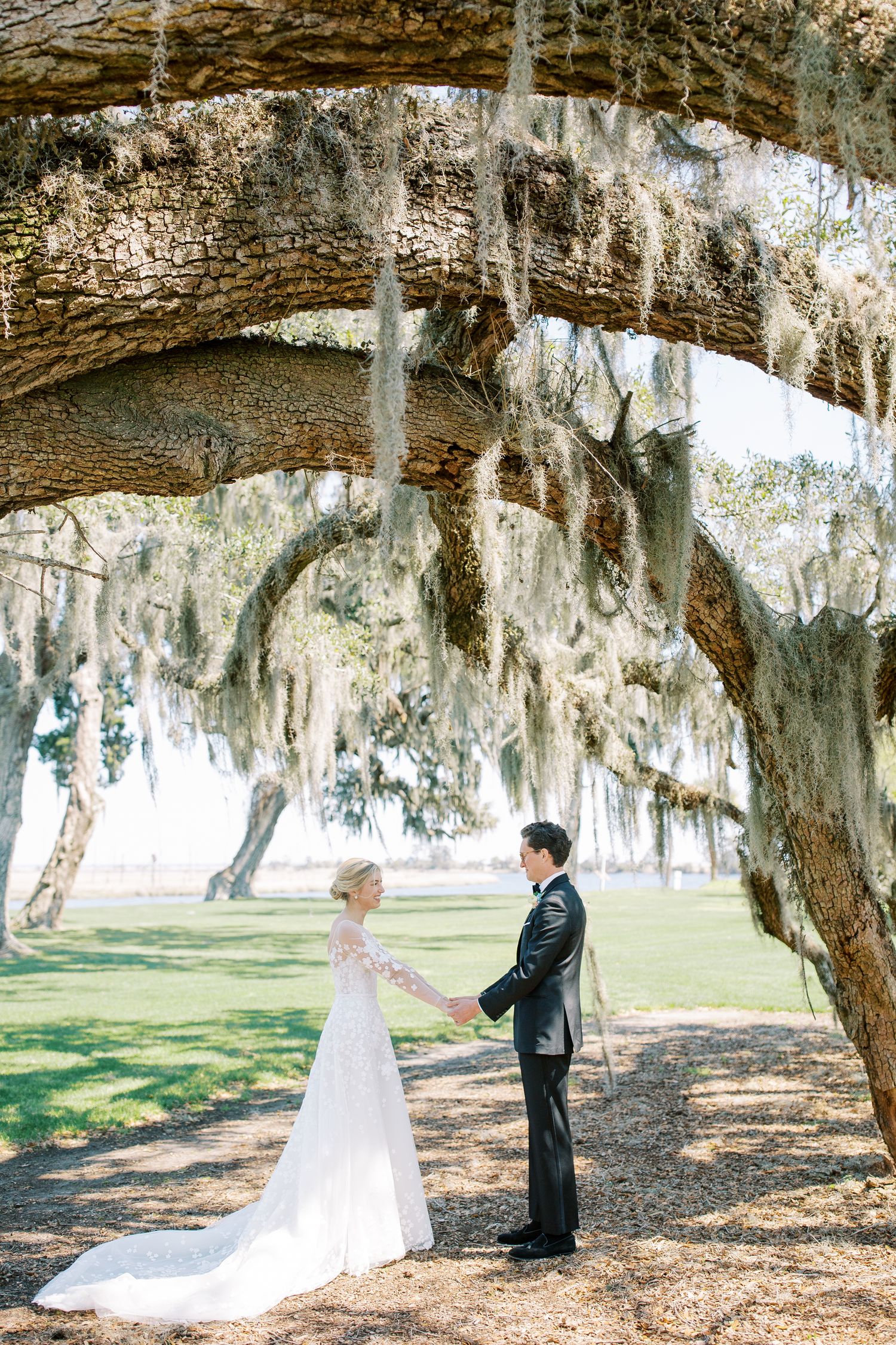 A couple shares romantic moments under majestic Spanish moss-draped oak trees in a serene outdoor setting.