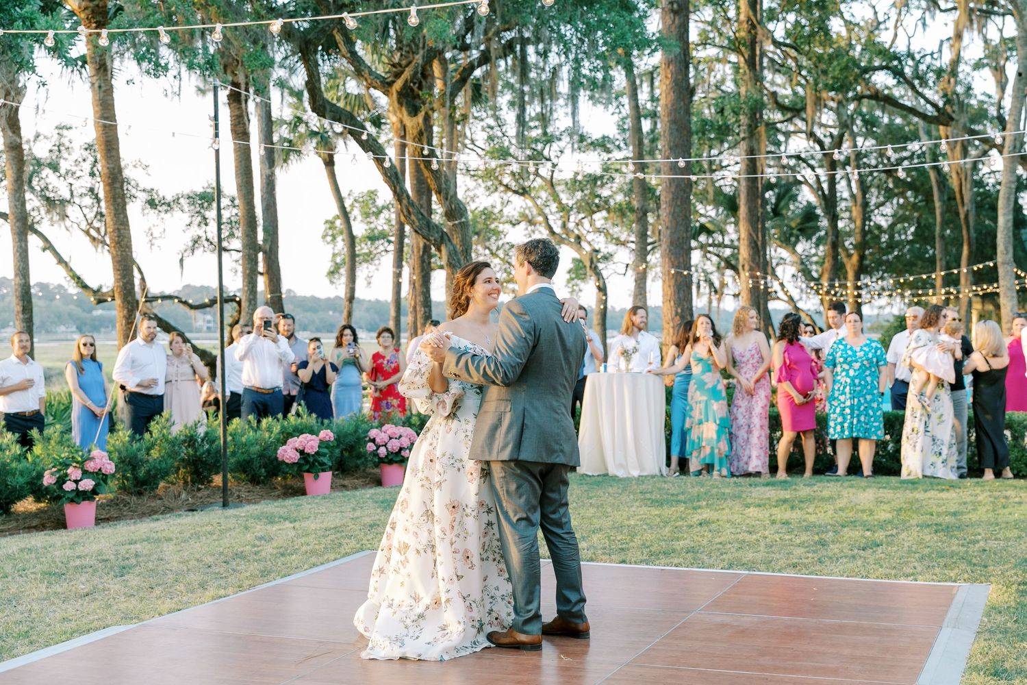 Panoramic view of outdoor wedding ceremony with guests gathered among tall pine trees.